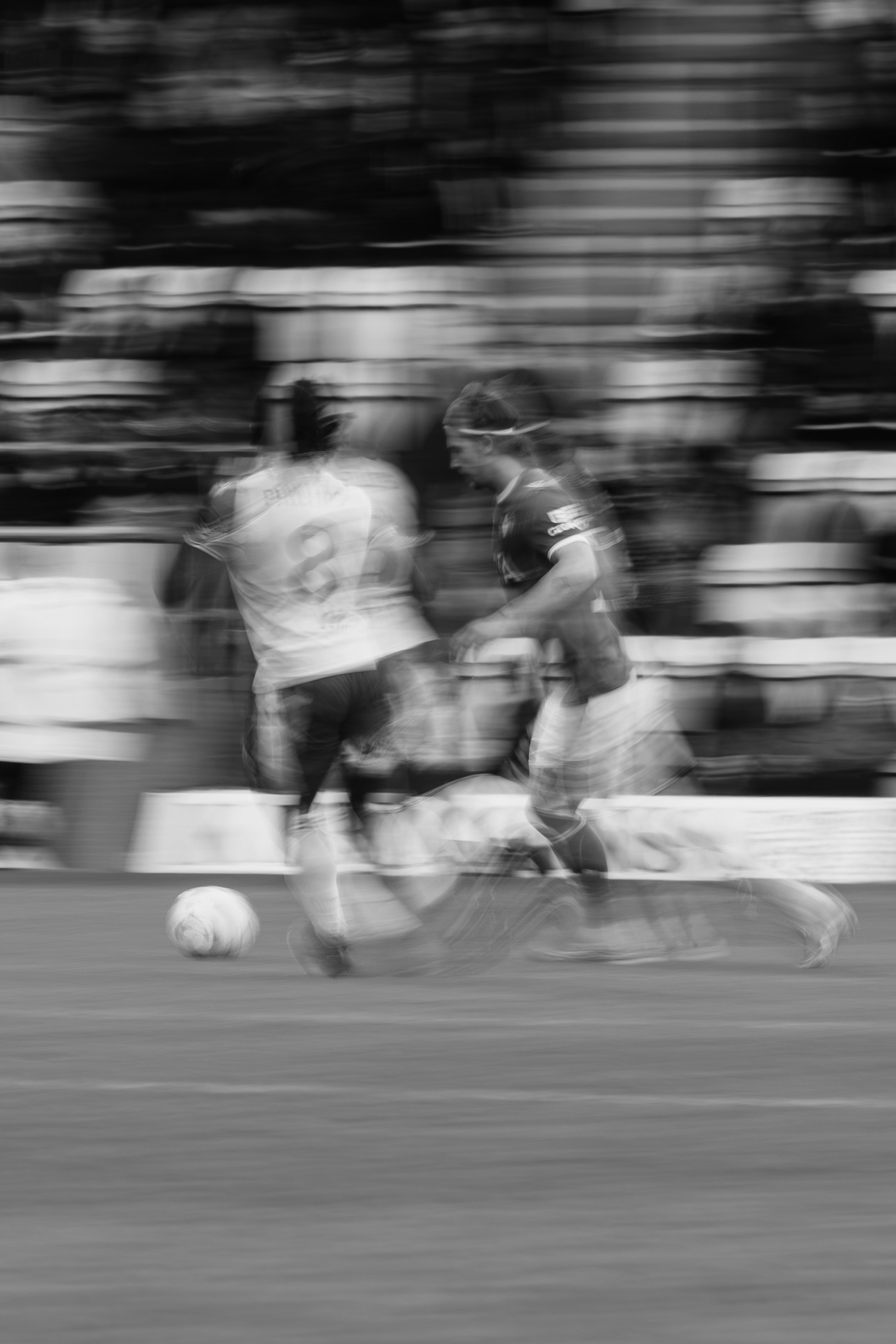 Dua pemain sepak bola bergerak selama pertandingan.