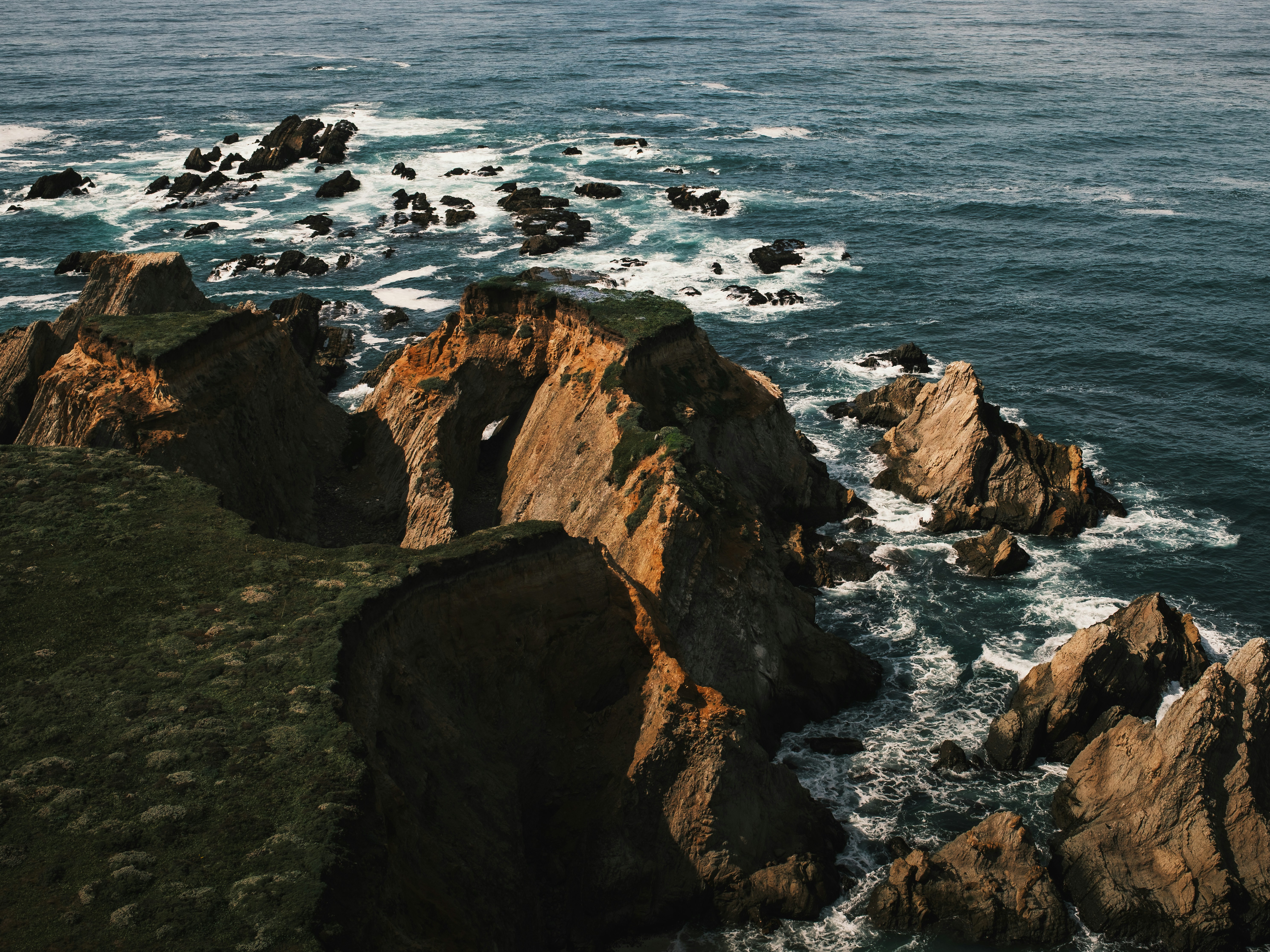 Rocky coastline with waves crashing against cliffs.