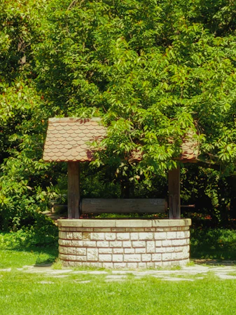 Stone well with wooden roof in lush green garden