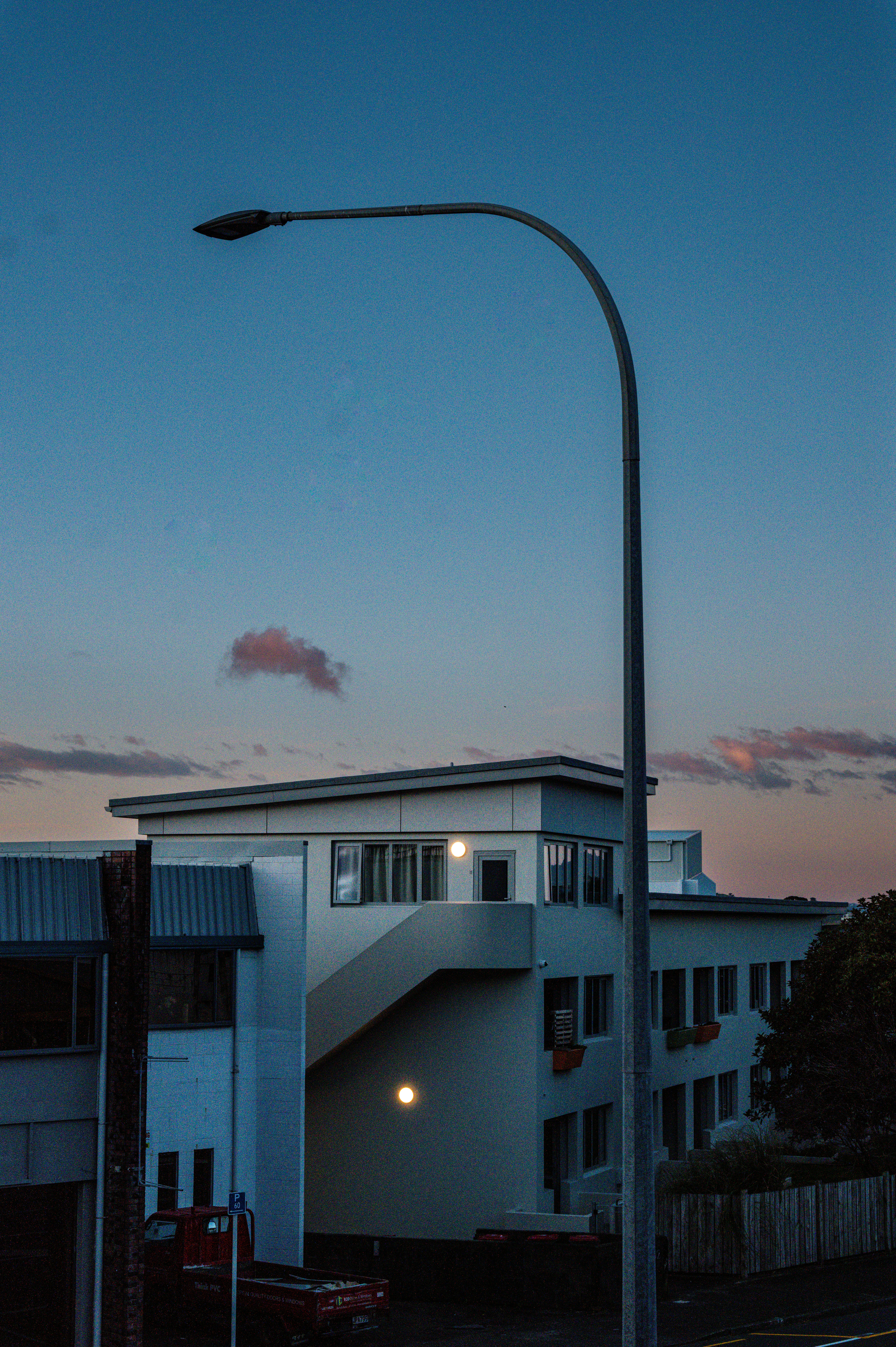 Poste de luz em frente a um prédio moderno ao entardecer