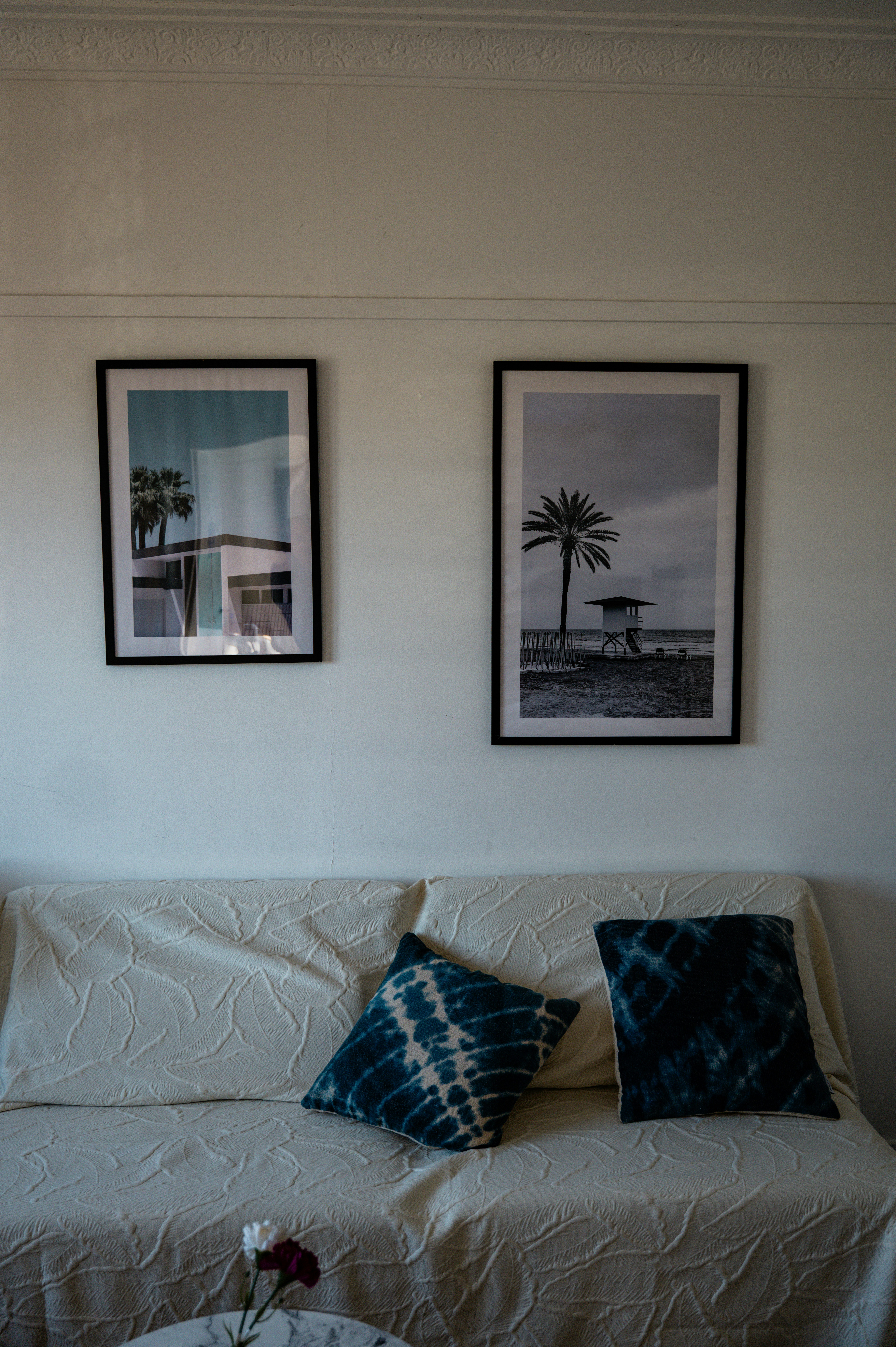 Sofá com almofadas decorativas e arte de praia emoldurada.