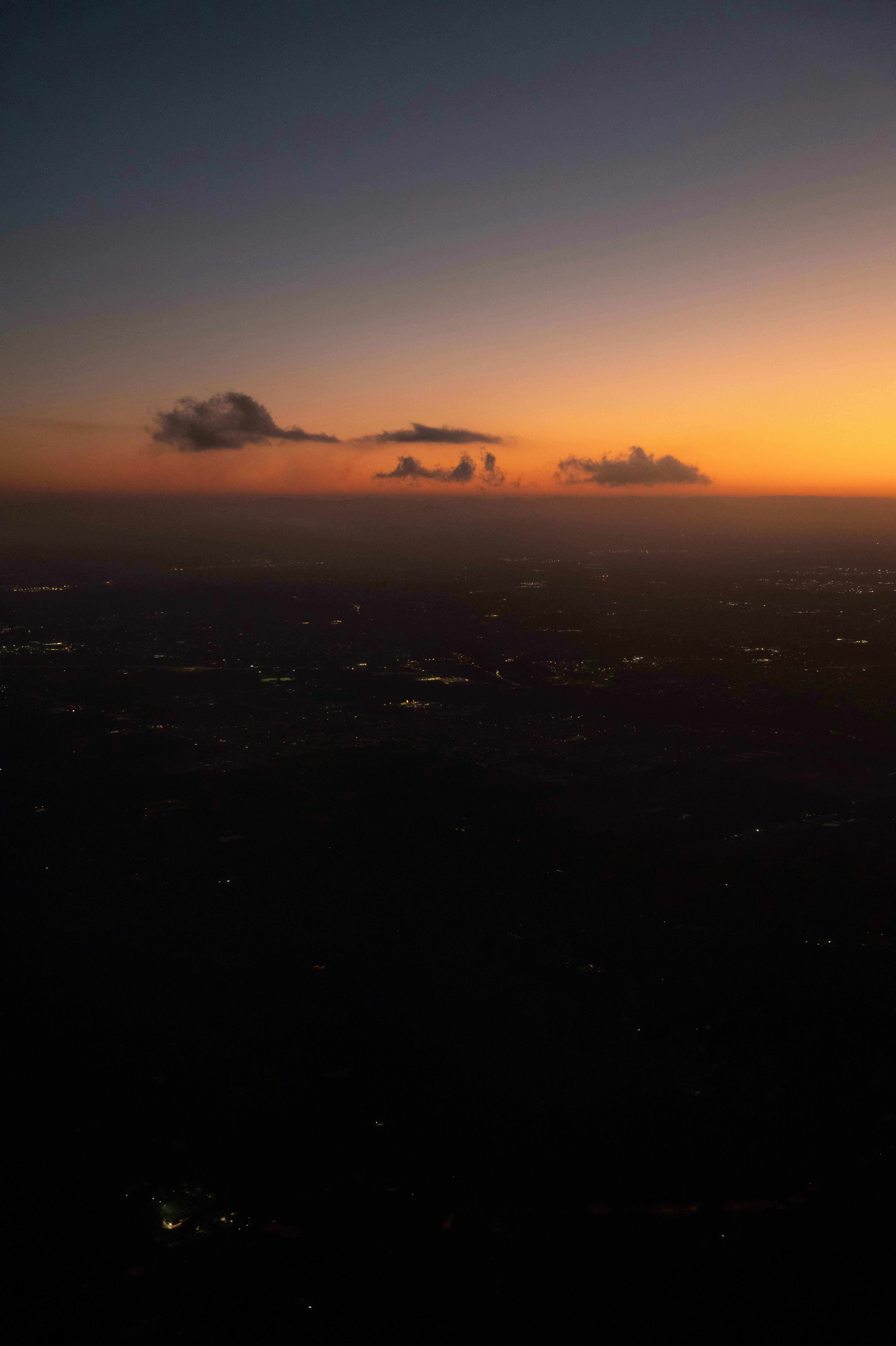 Vista aérea das luzes da cidade ao entardecer com céu ao pôr do sol.