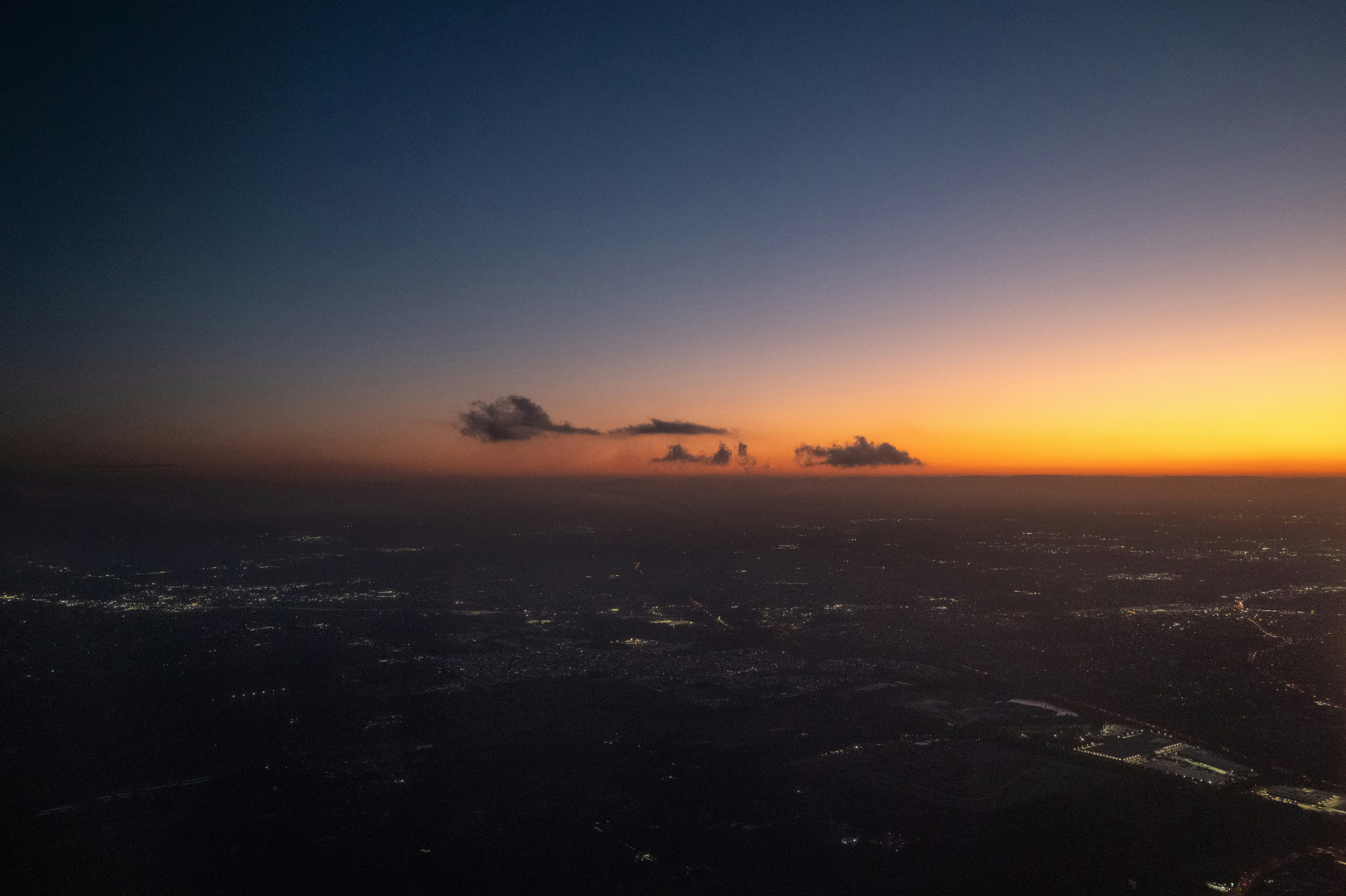 As luzes da cidade brilham sob um vibrante céu ao pôr do sol.