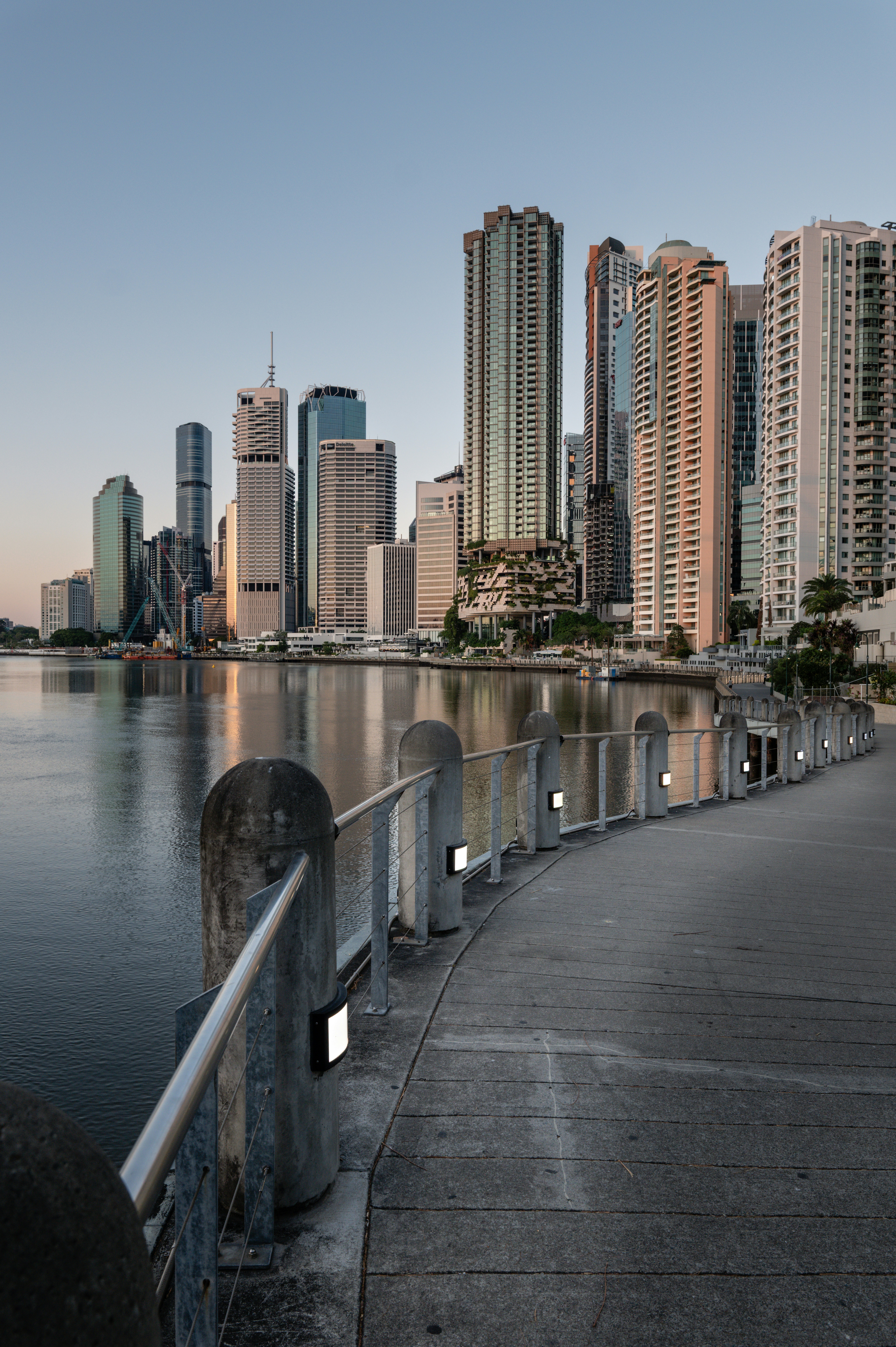 O horizonte moderno da cidade refletido em um rio calmo ao amanhecer.