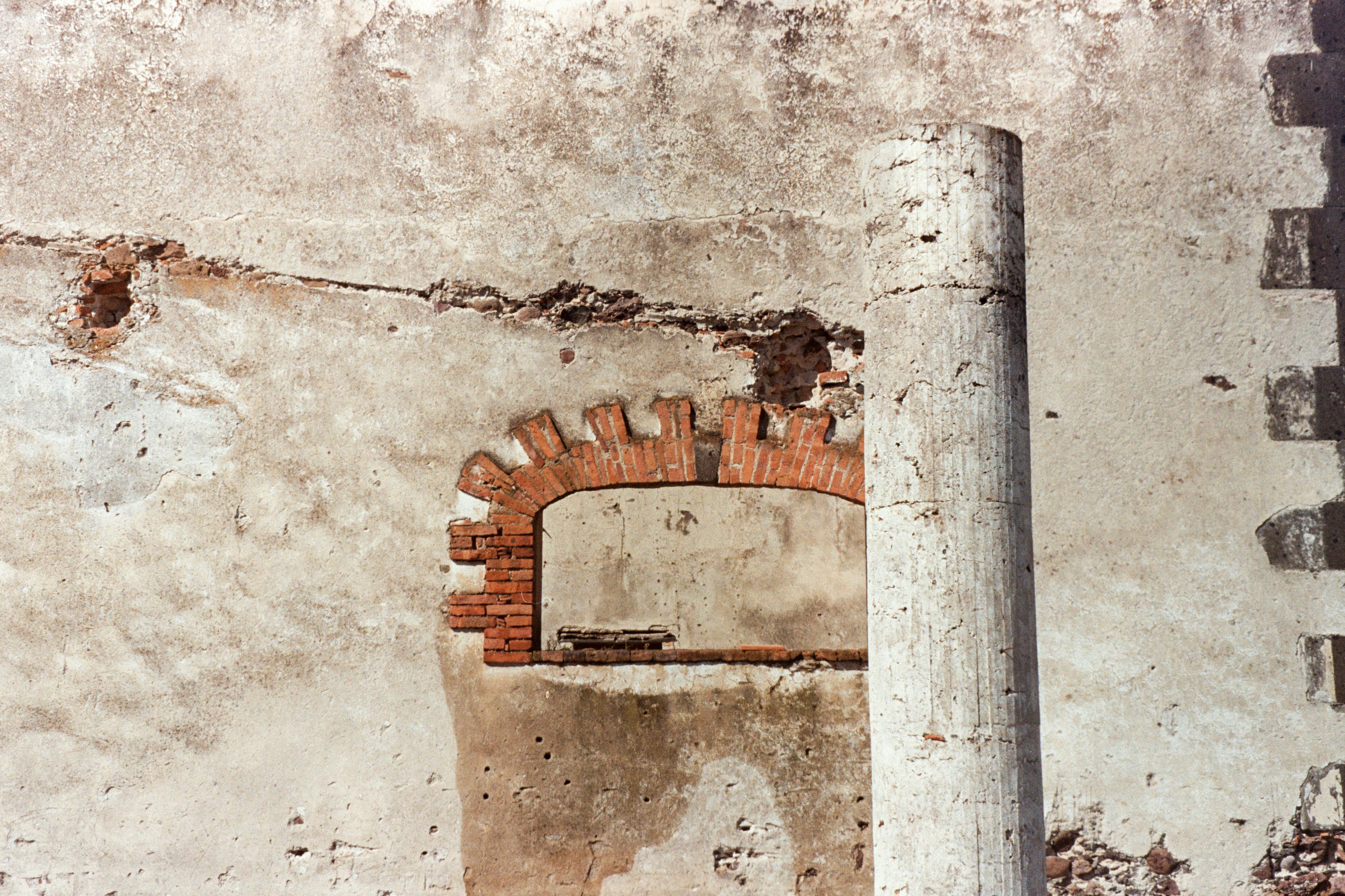 Old weathered wall with a brick archway and column