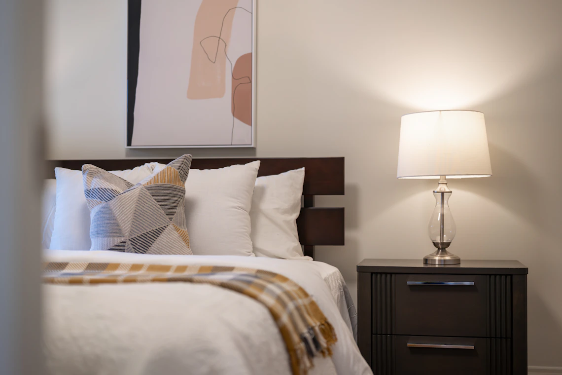 Refined bedroom with upholstered bed, nightstand, lamp, and layered bedding