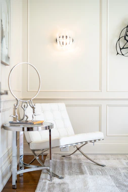 Modern white chair with metallic accents and side table.