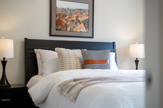 A neatly made bed with pillows and lamps