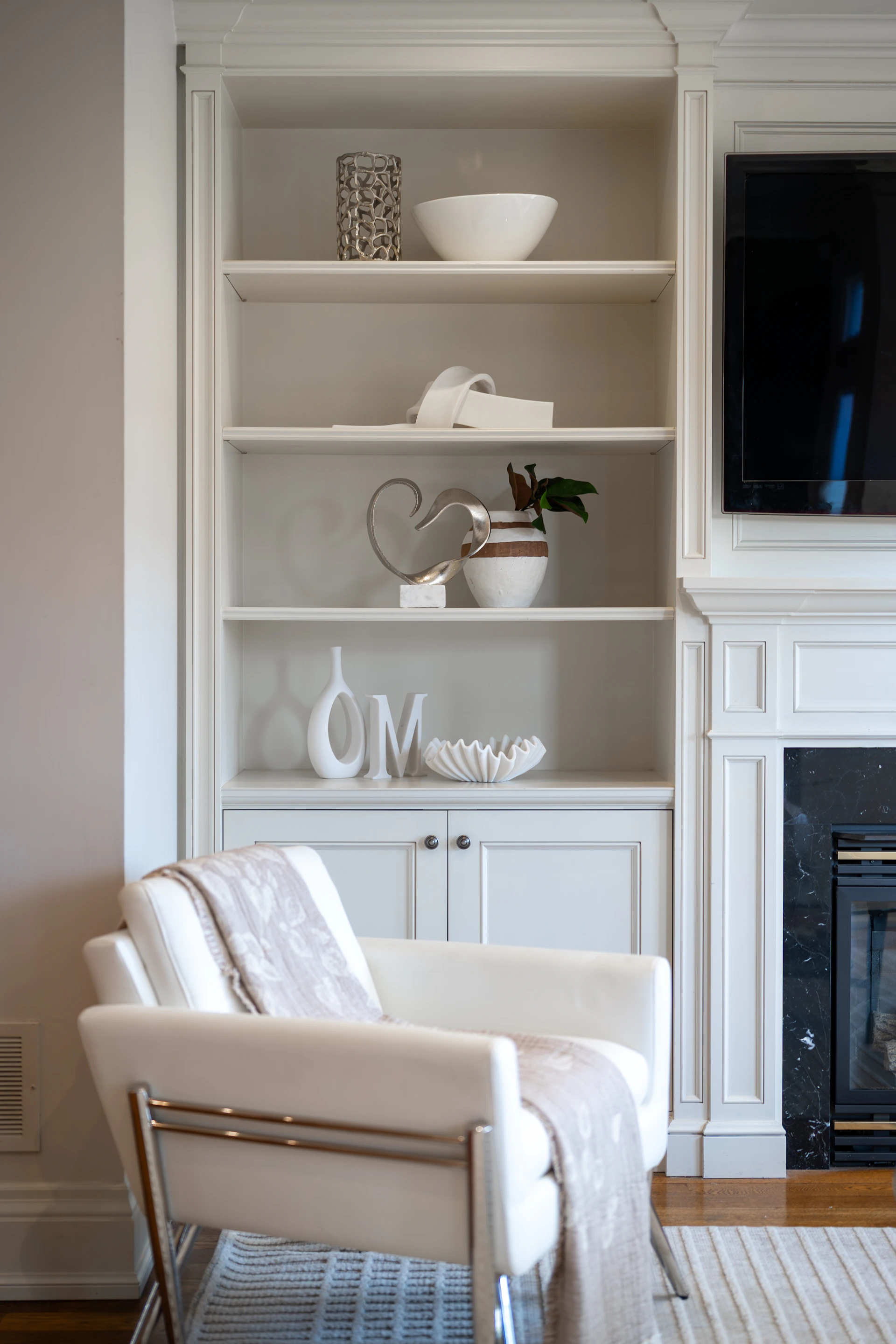 White armchair in front of built-in shelves