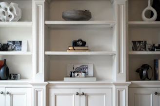White built-in shelves display decorative items and cameras.