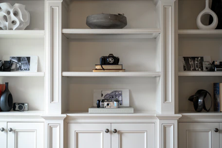 White built-in shelves display decorative items and cameras.