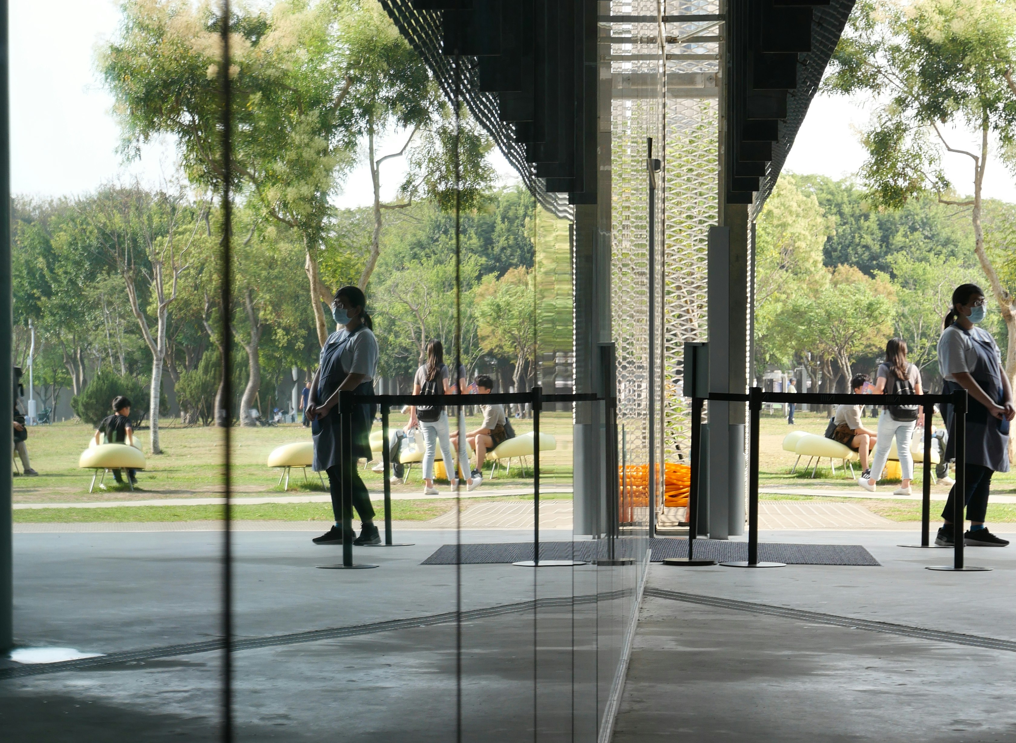 Pessoas paradas perto de portas de vidro com reflexos