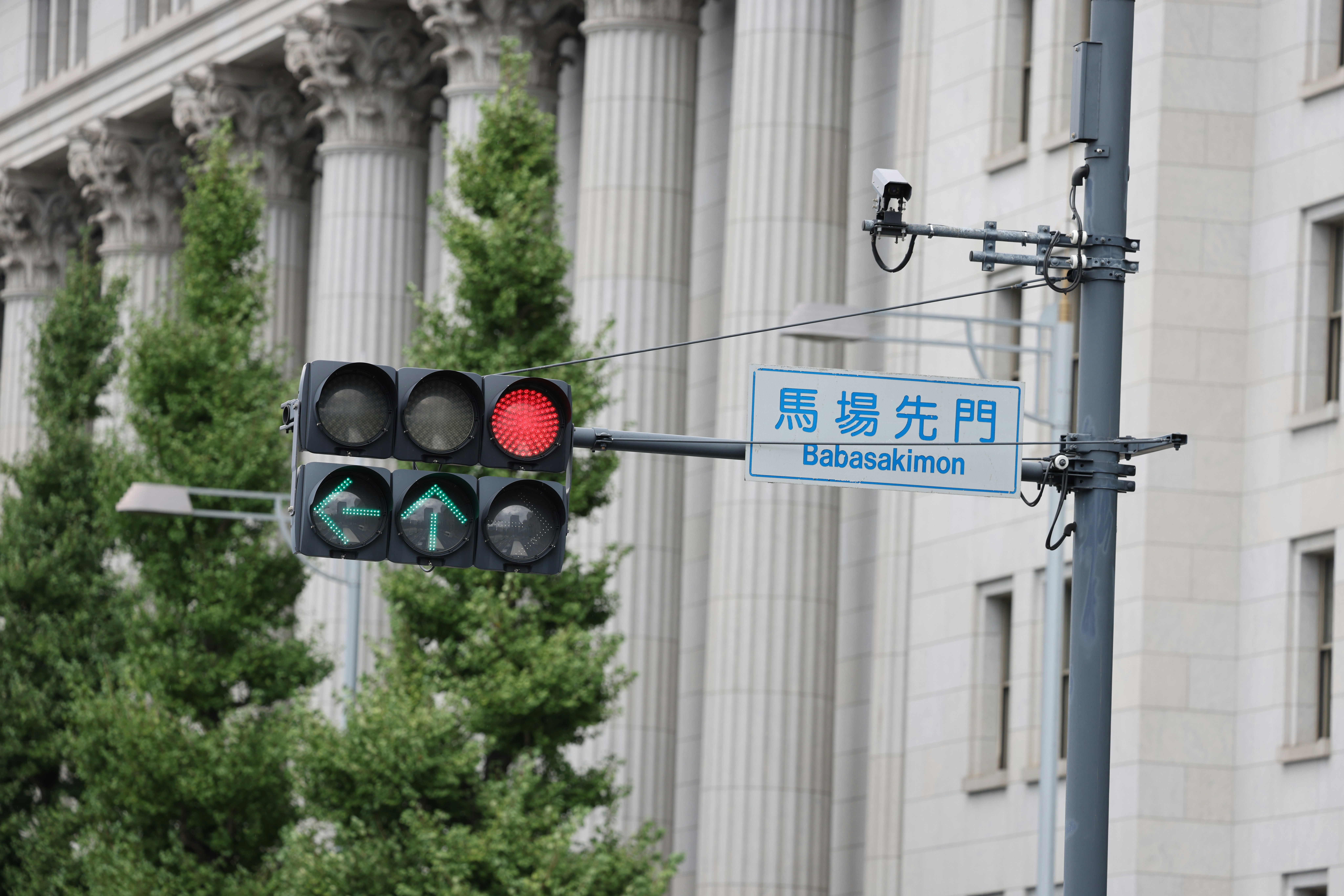 Traffic light showing red with building and trees