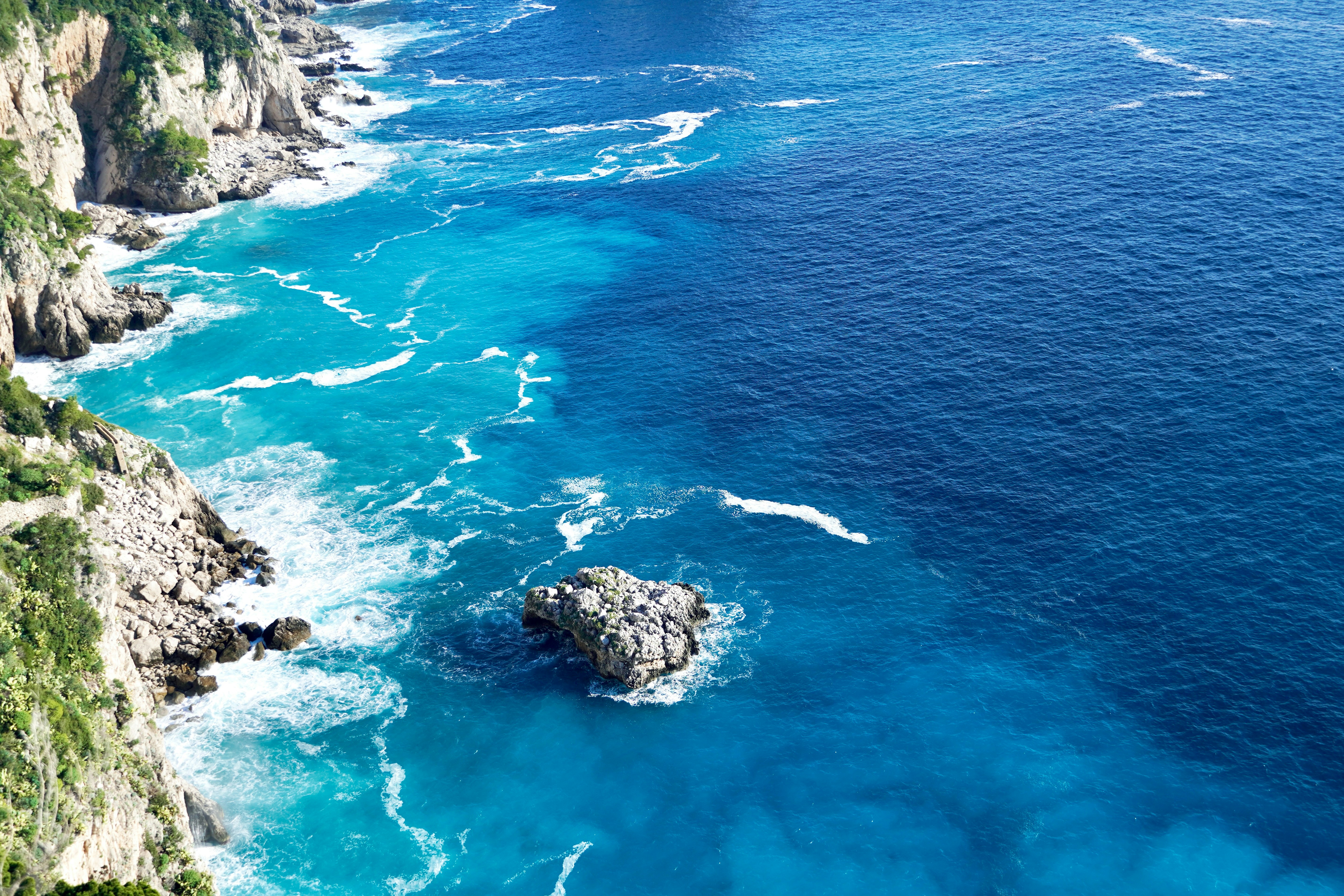 Las olas turquesas del océano rompen contra acantilados rocosos.