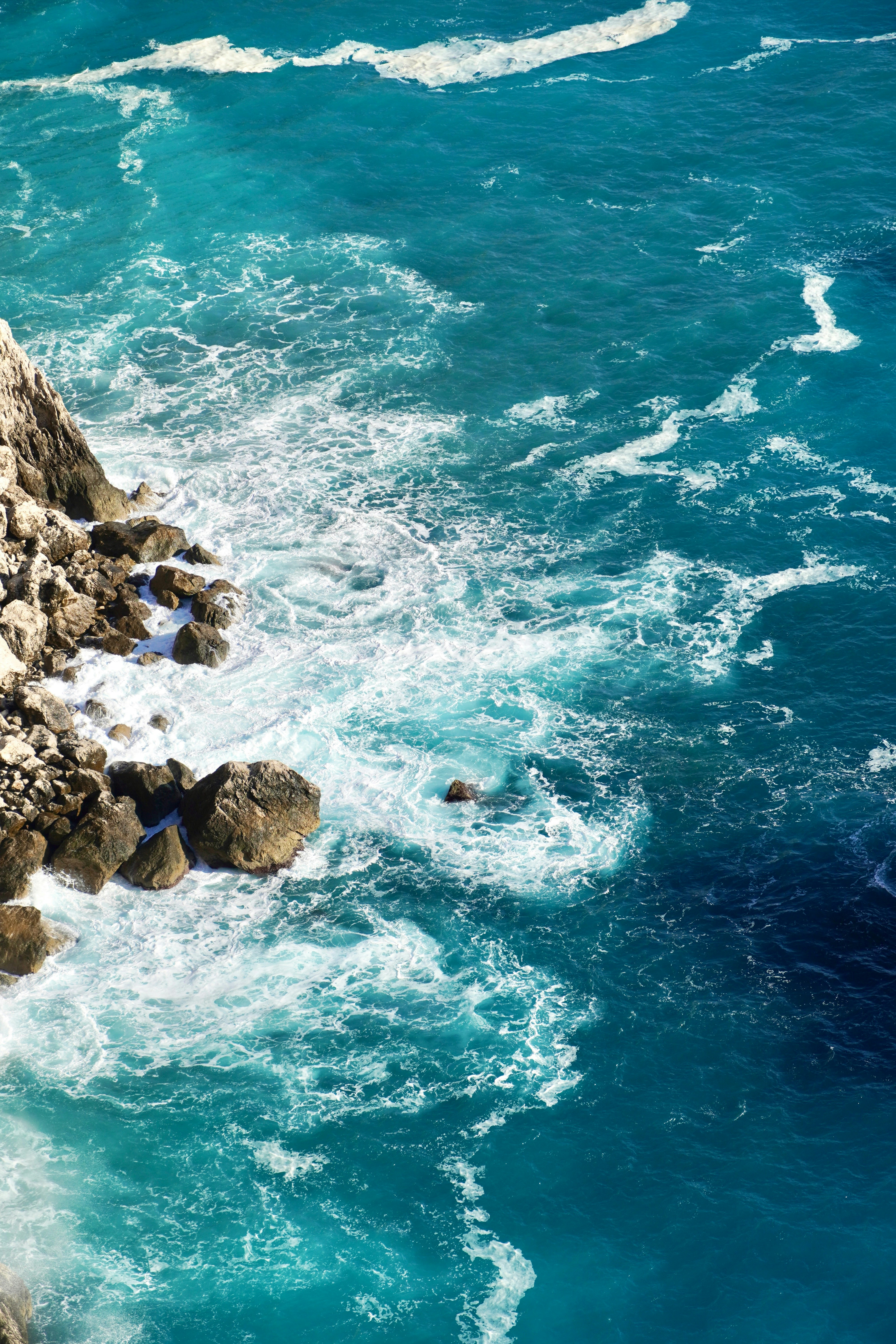 Las olas turquesas del océano rompen contra la costa rocosa