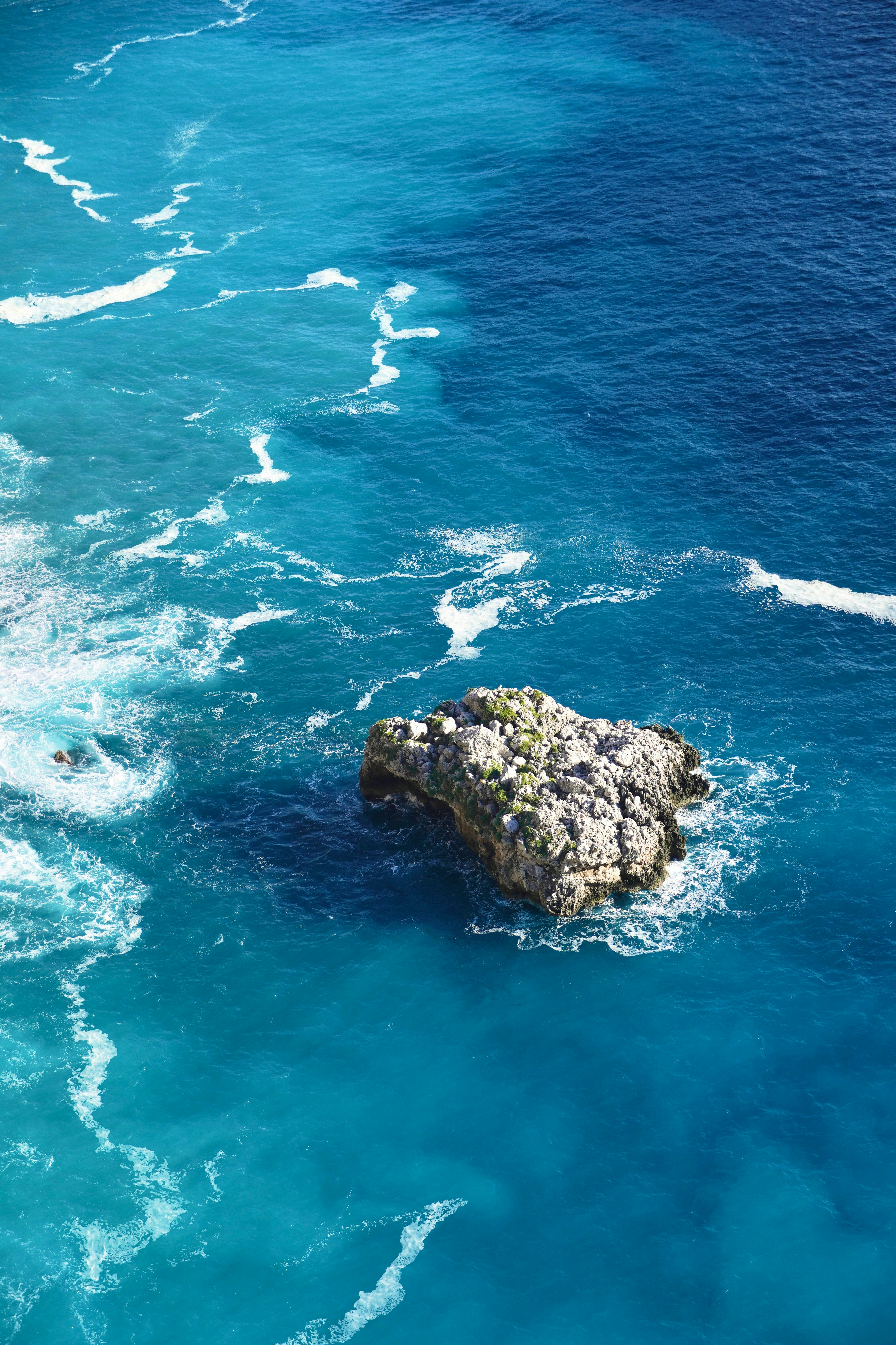 Formación rocosa en aguas oceánicas azul clara con olas