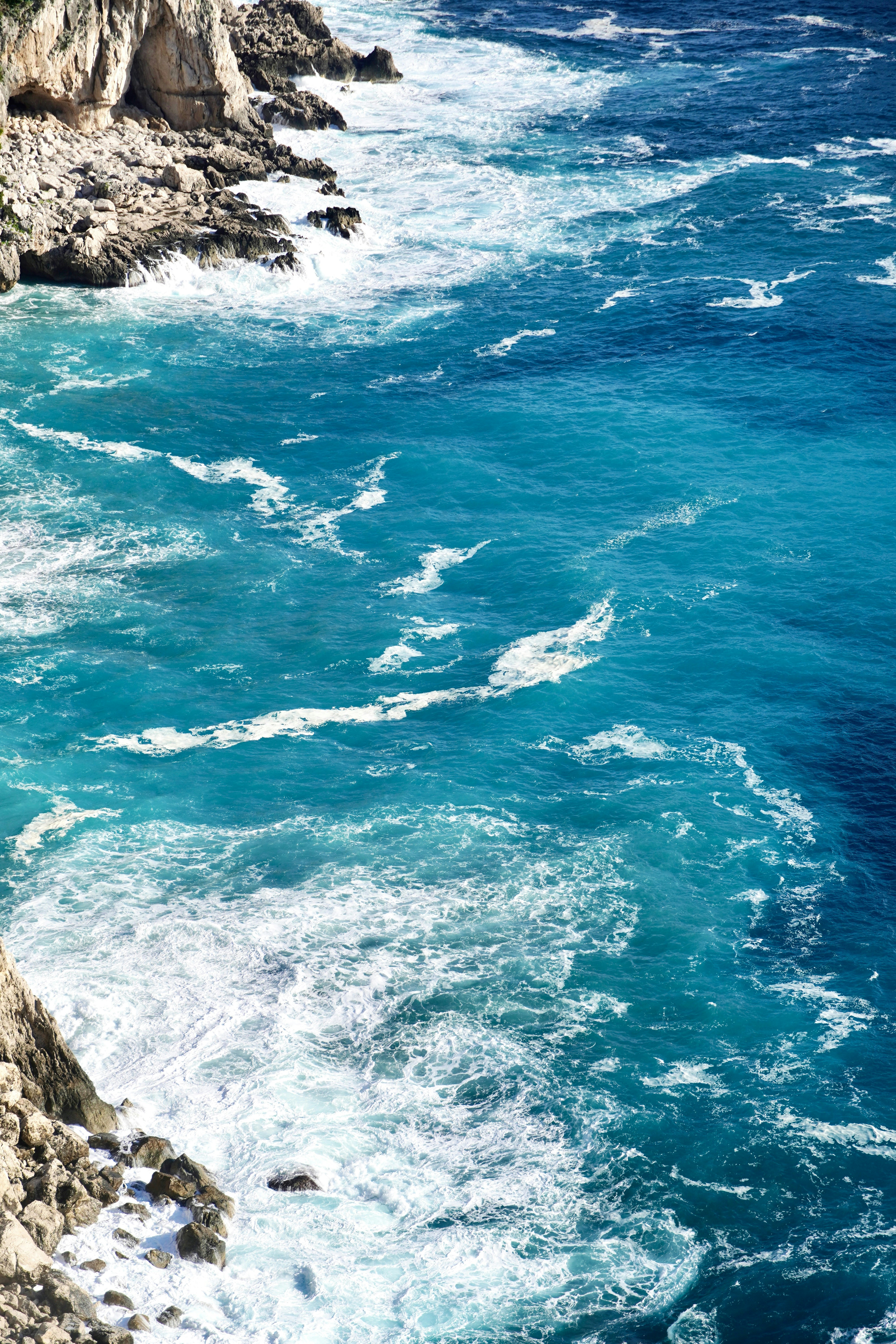 Las olas turquesas del océano rompen contra la costa rocosa