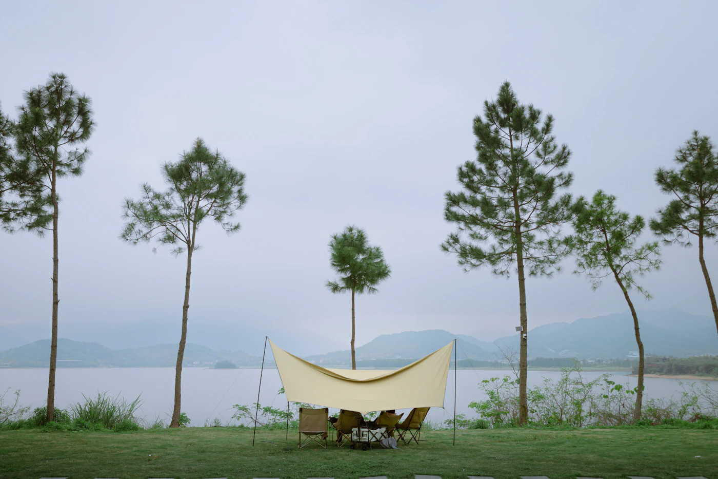 Lakeside campsite with tarp shelter and folding chairs