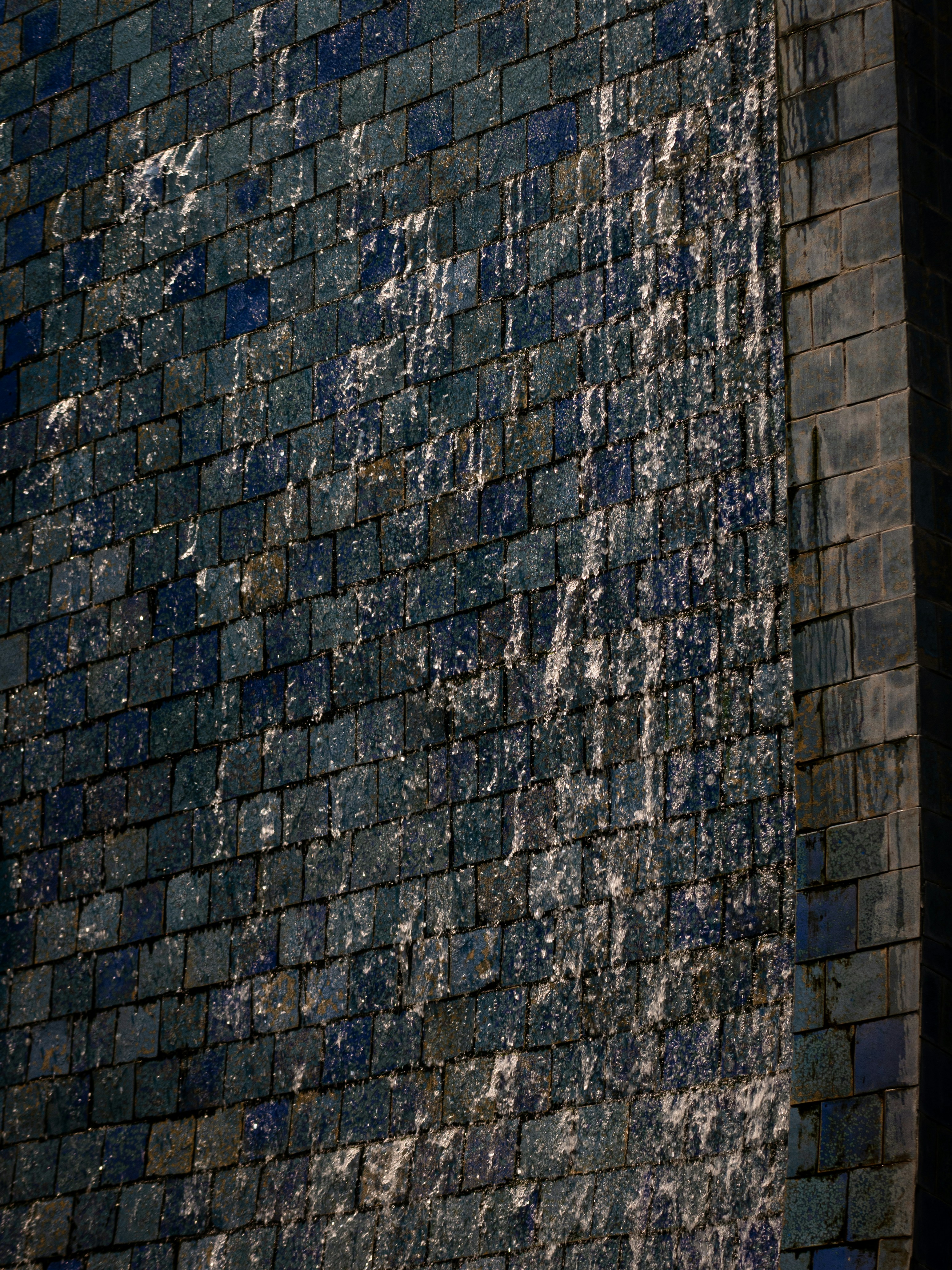 Water cascading down a dark tiled wall