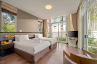 Modern hotel room with two beds and large windows.