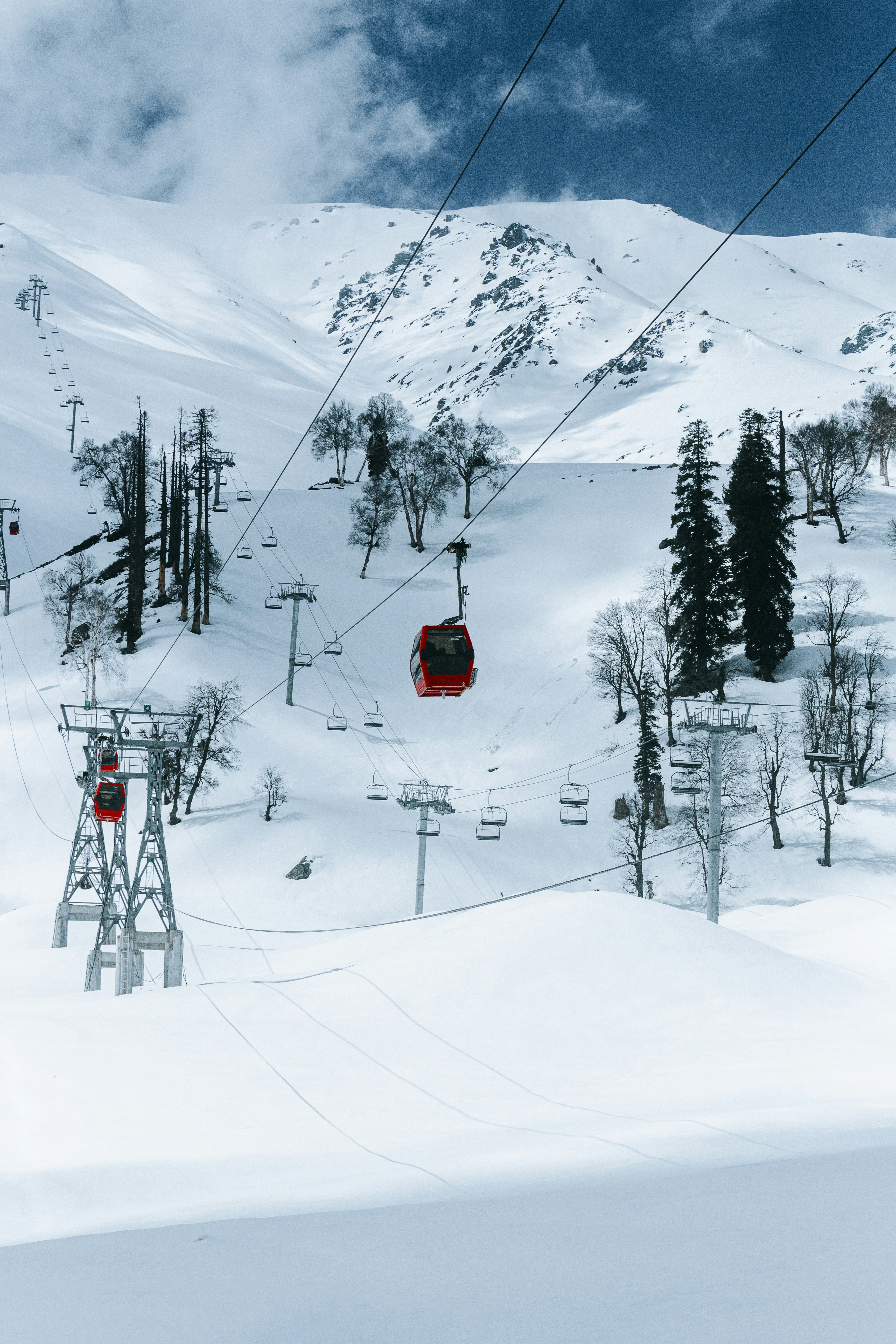 Cable cars ascend a snowy mountain slope.