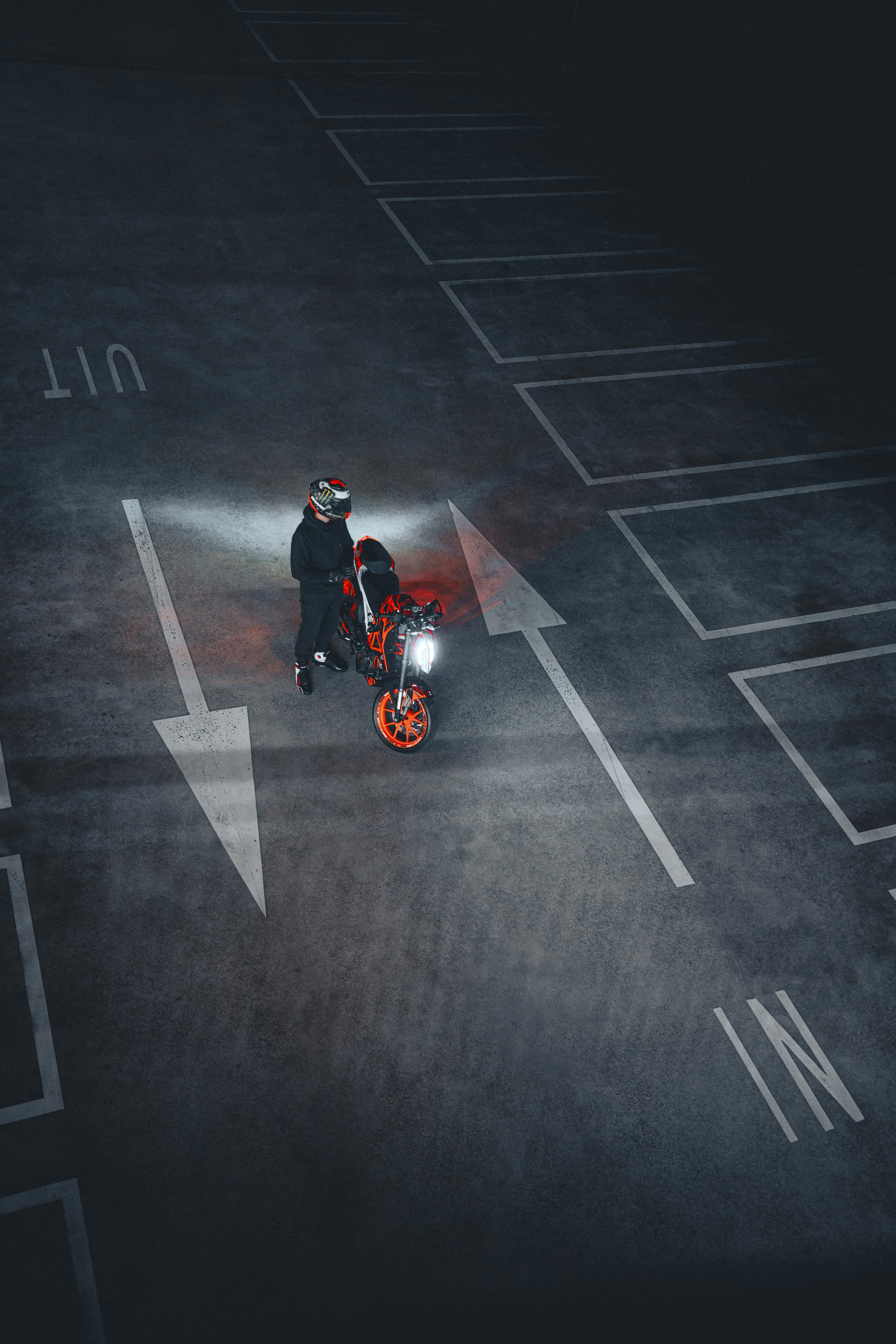 A person with a motorcycle in a parking lot.