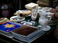 Stacks of hermes magazines and decorative plates on table.