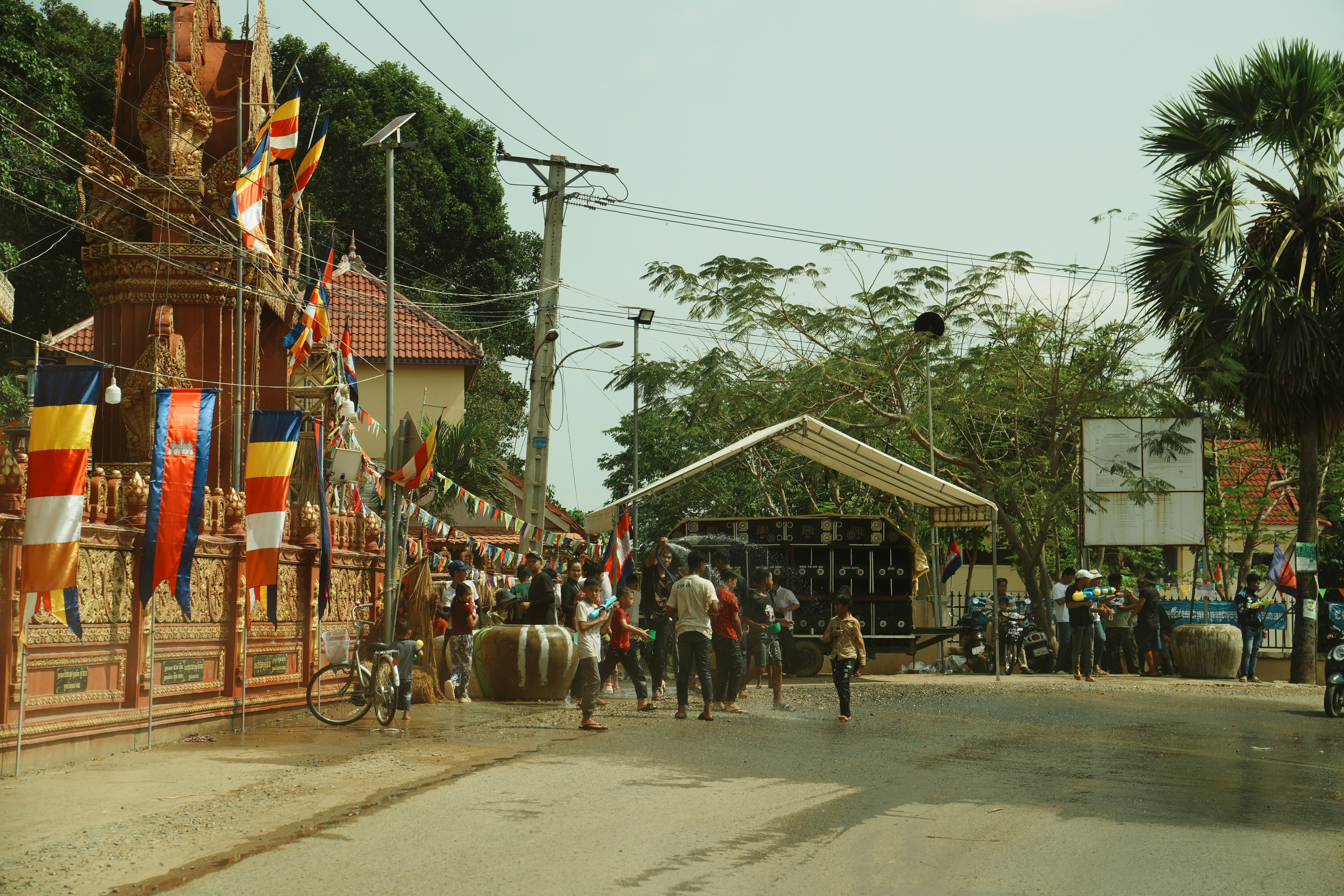 People gather near a decorated entrance with flags and tents.