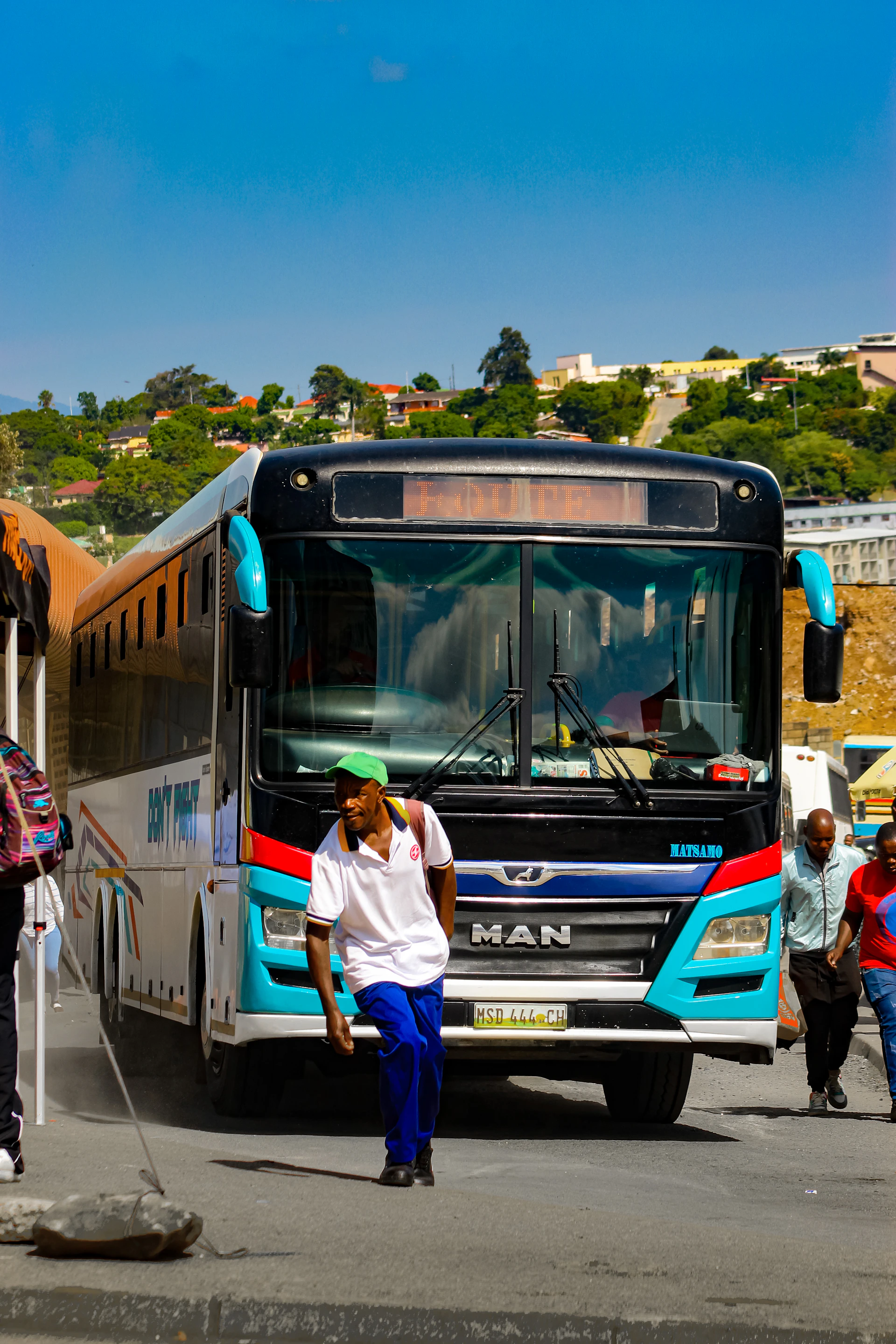 A man rests by a bus at a station
