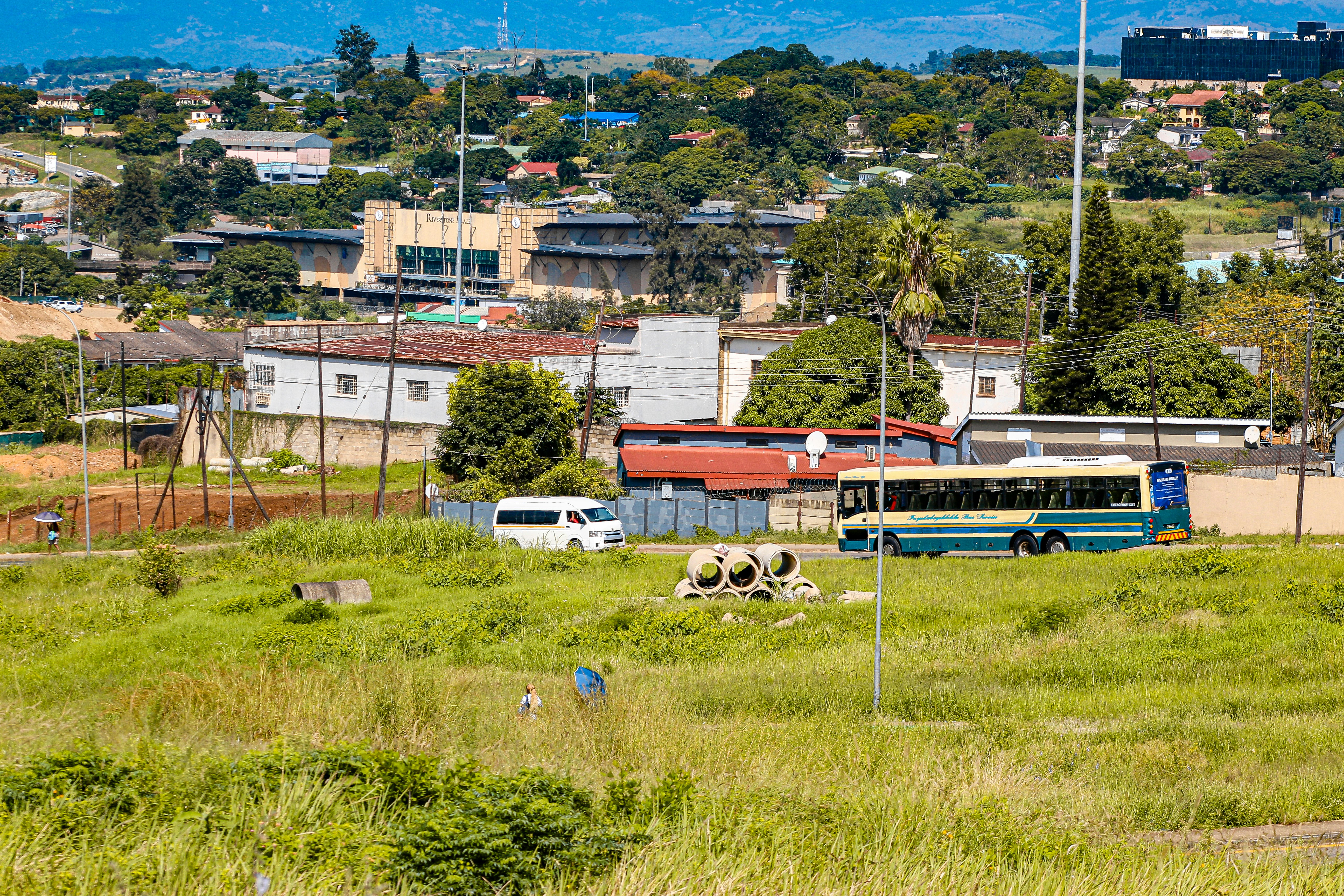 Bus and van on a grassy hill overlooking buildings.