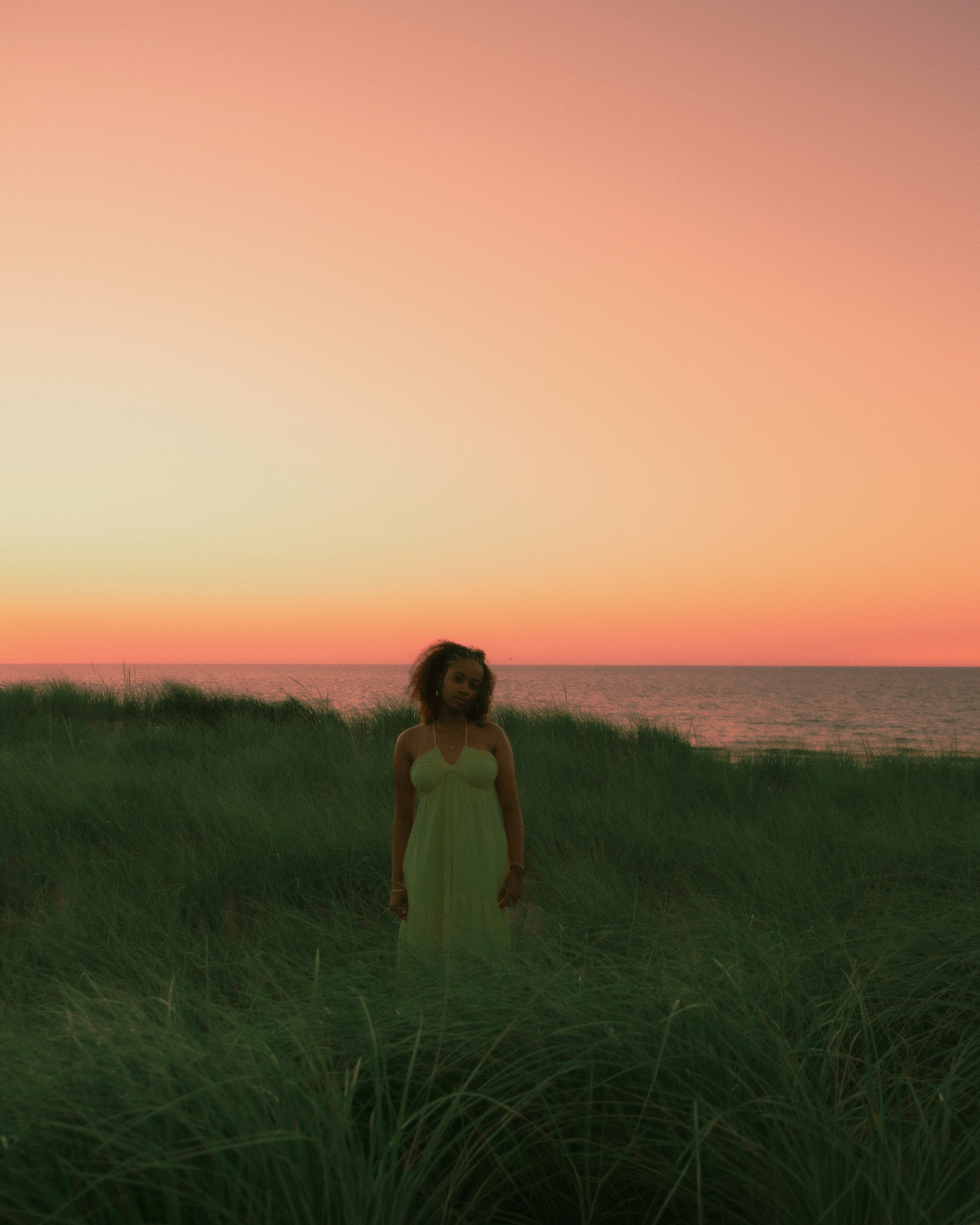 Woman standing in tall grass at sunset