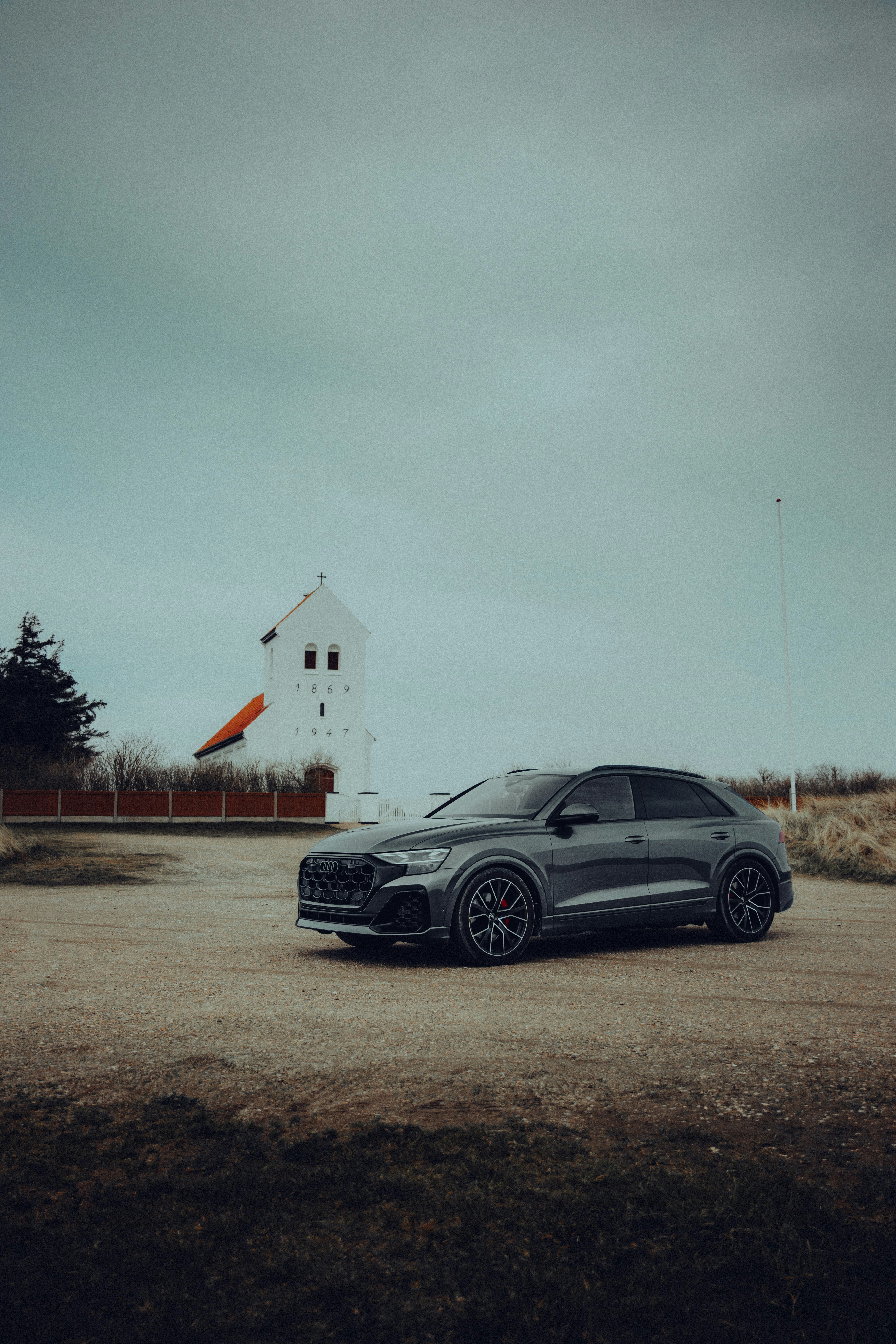 A dark grey suv parked near a white church.