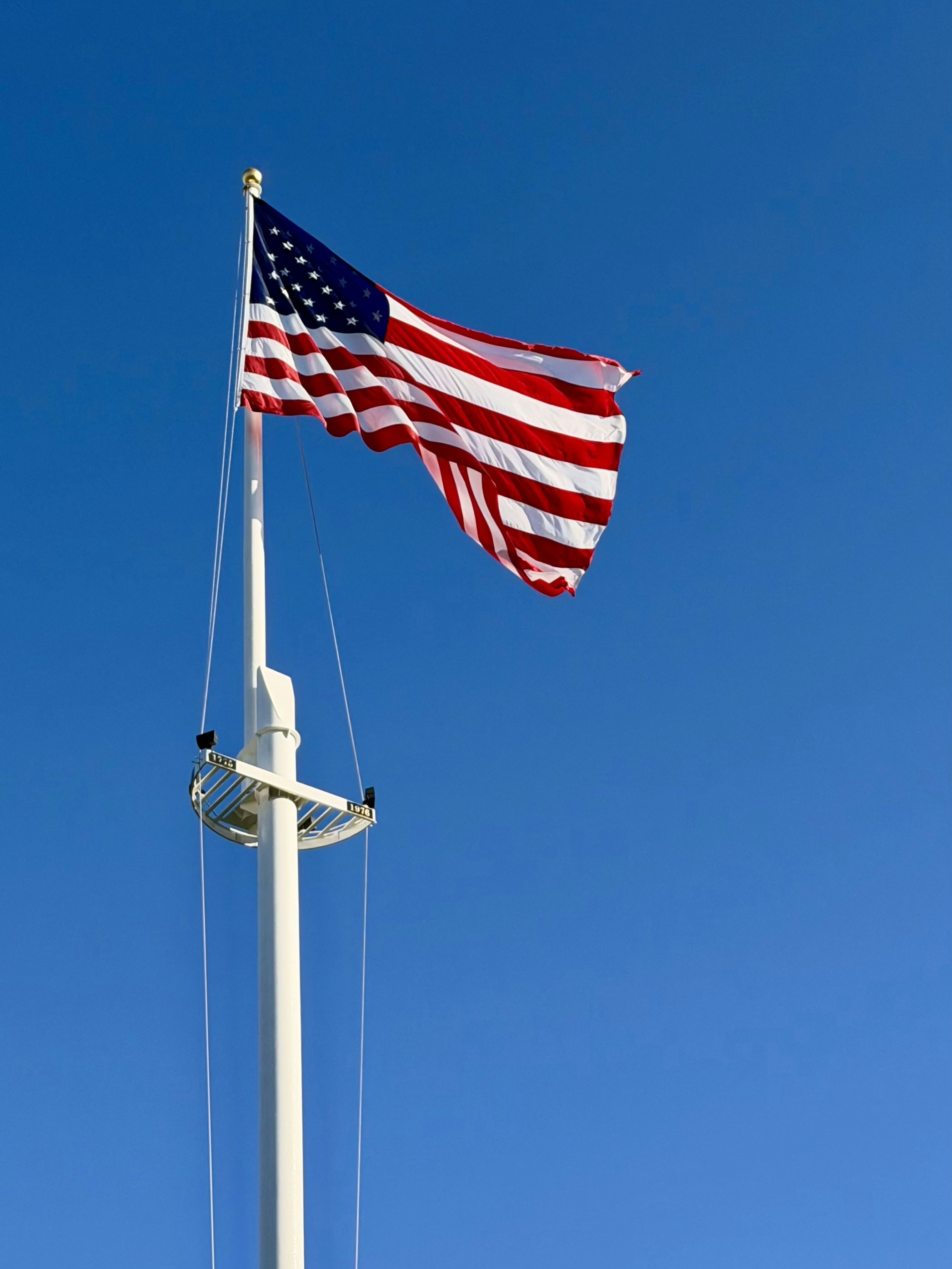 Bandiera americana che sventola su un palo contro il cielo azzurro