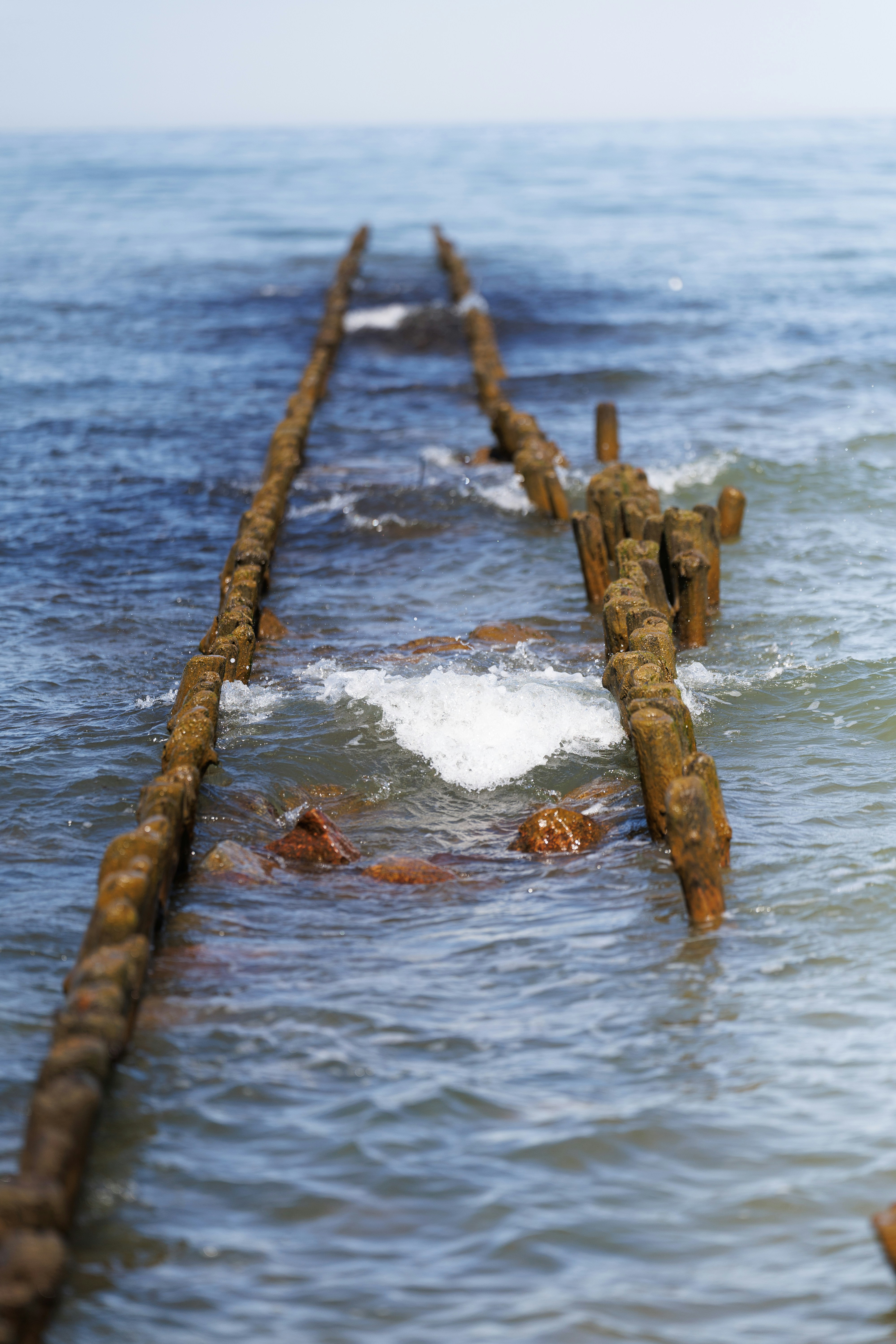 Weathered wooden structures submerged in ocean waves.