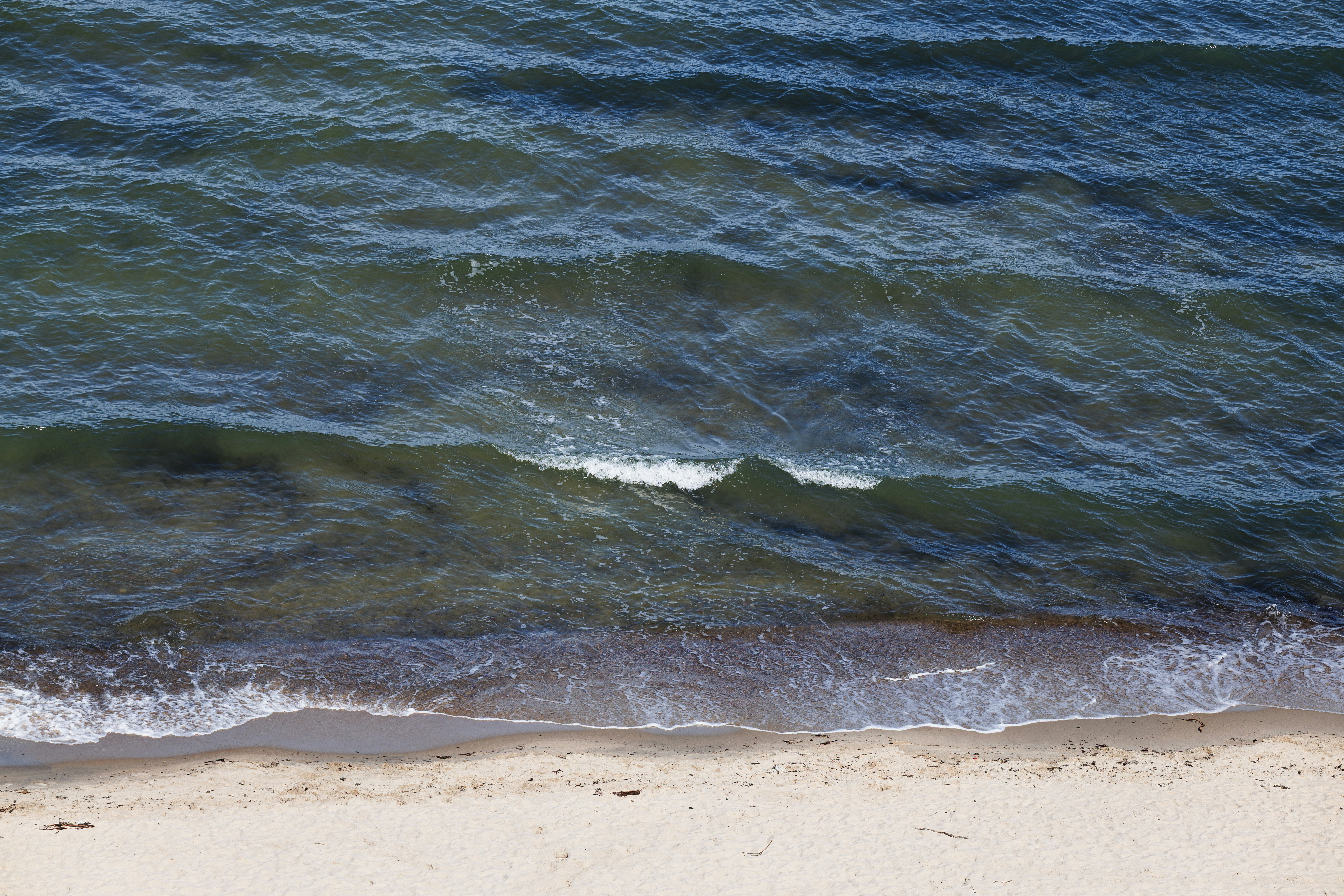 Gentle waves lap onto a sandy beach from the ocean.