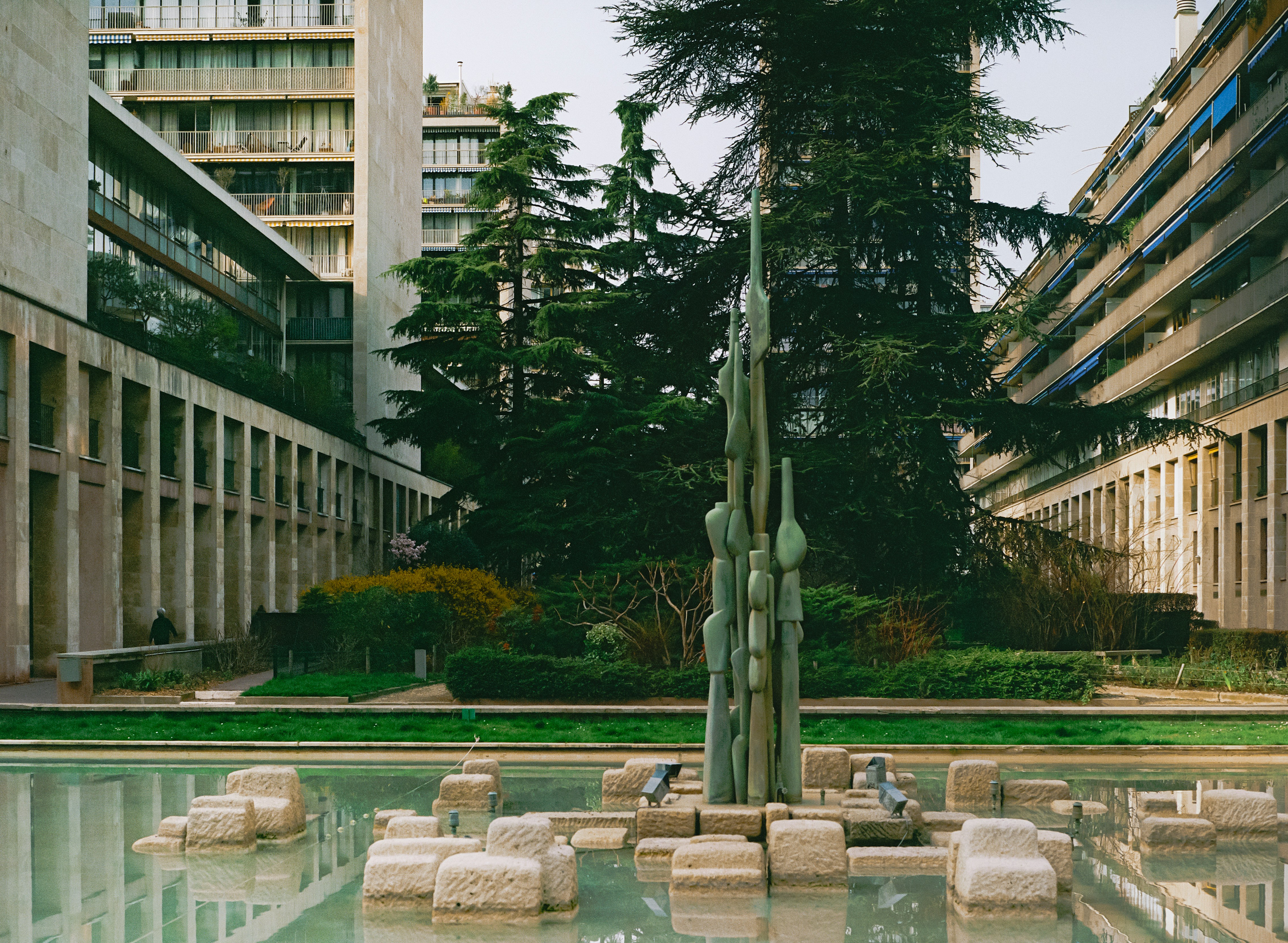 Modern buildings surround a central water feature with sculpture.