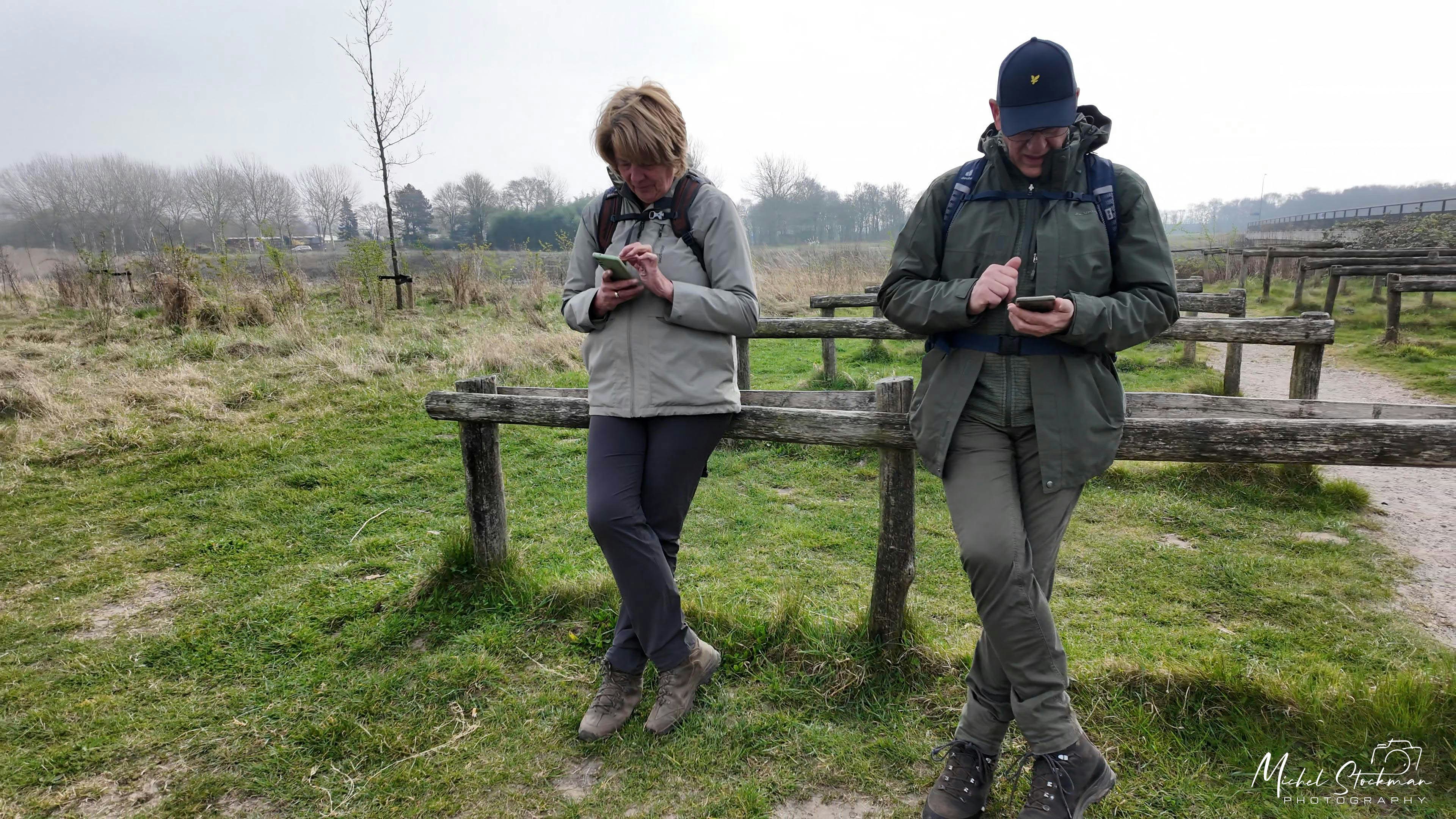 Two people looking at their phones outdoors