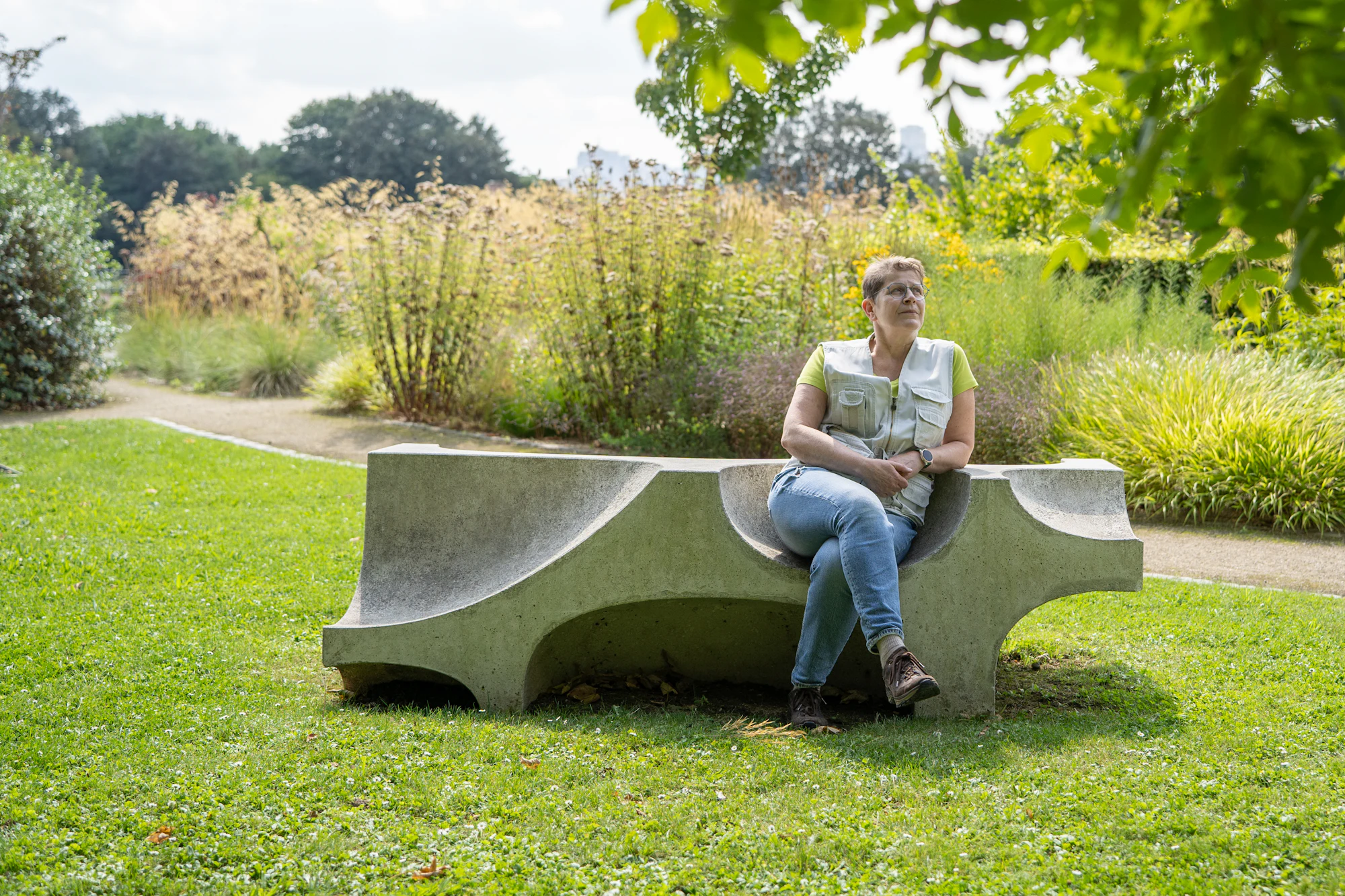 Une femme assise sur un banc de béton dans un parc