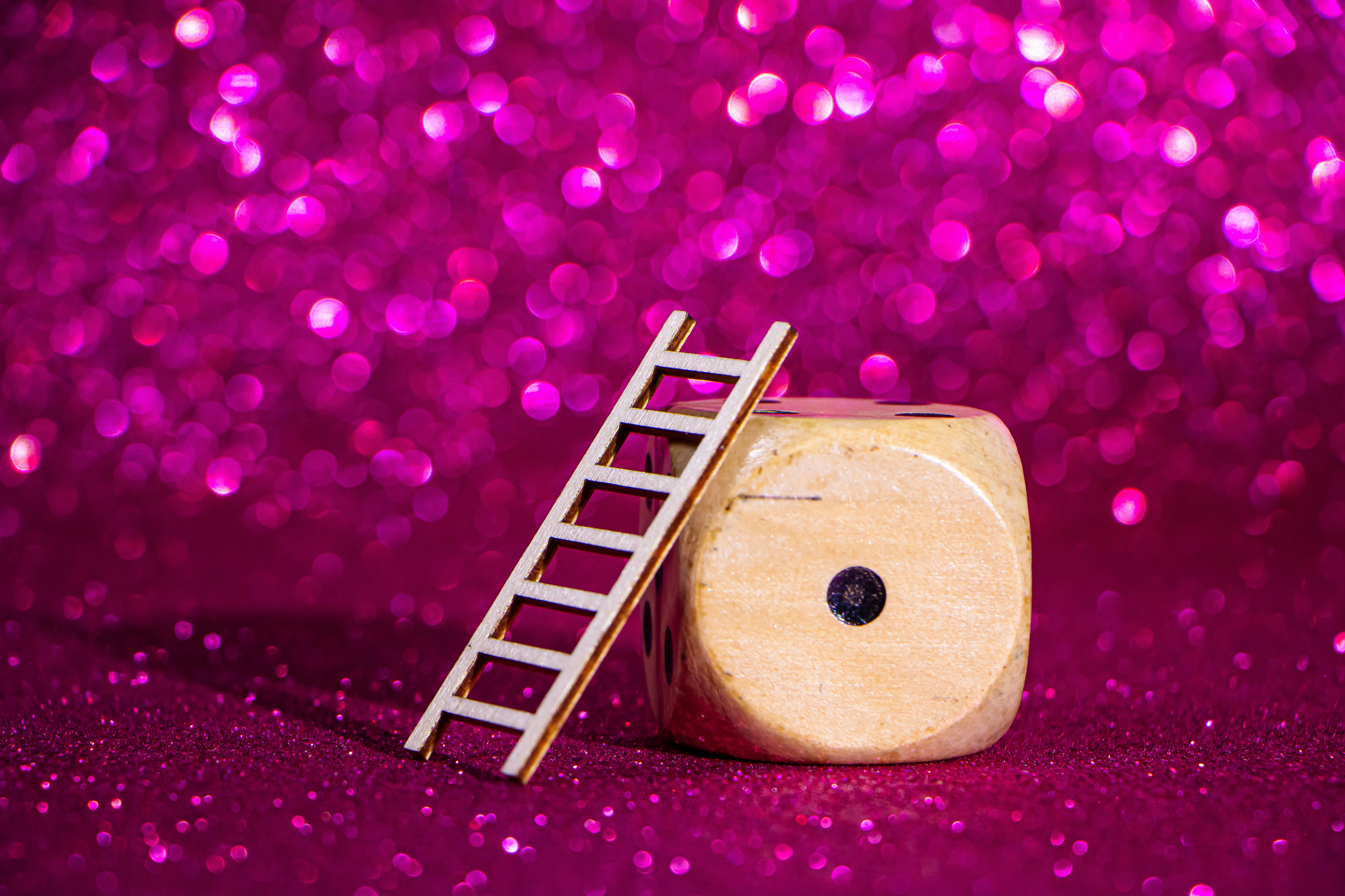 A small ladder rests against a large die.