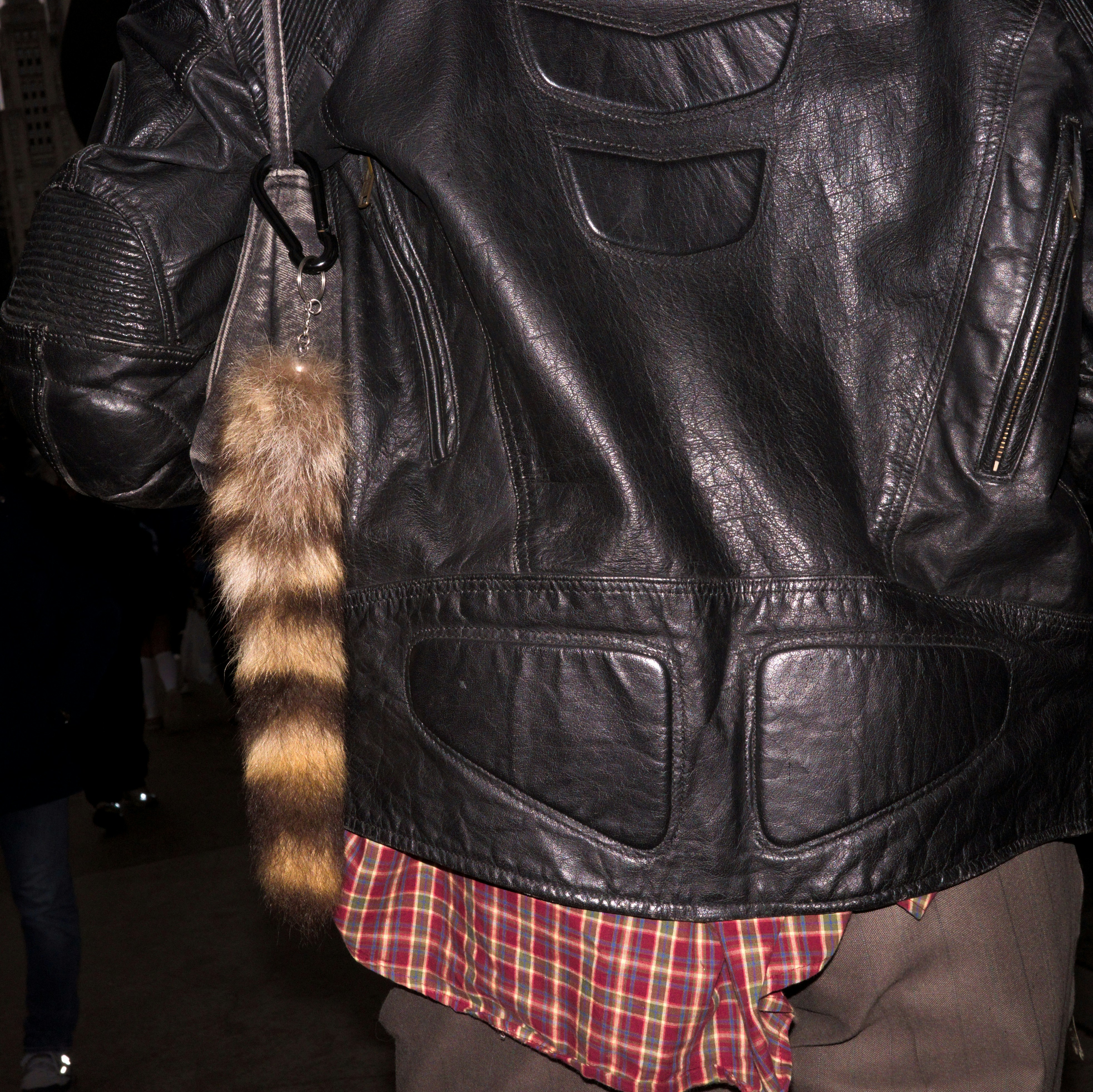 Person trägt eine Lederjacke mit einem Waschbärschwanz-Accessoire