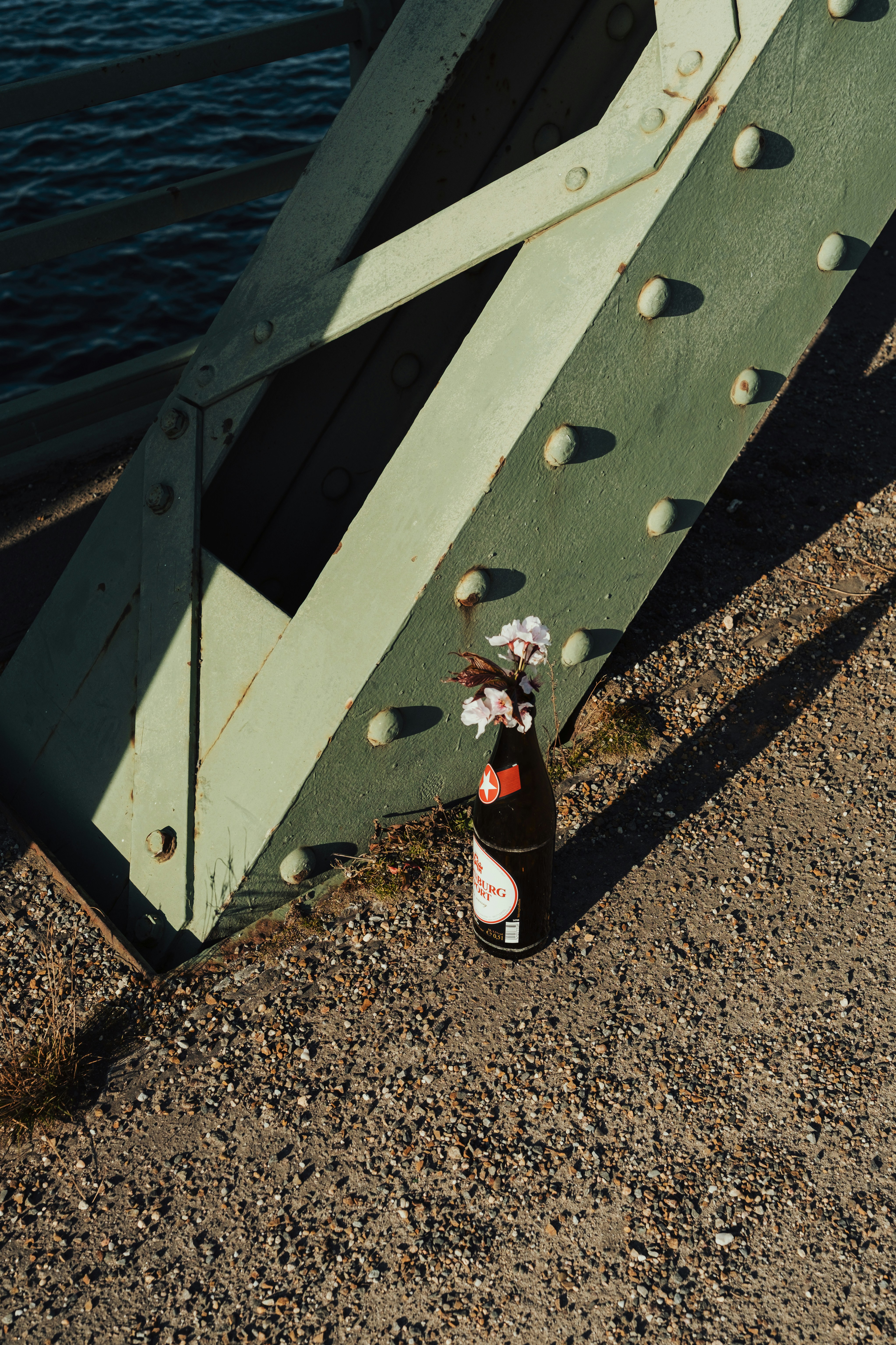 Bottle with flowers on bridge near water