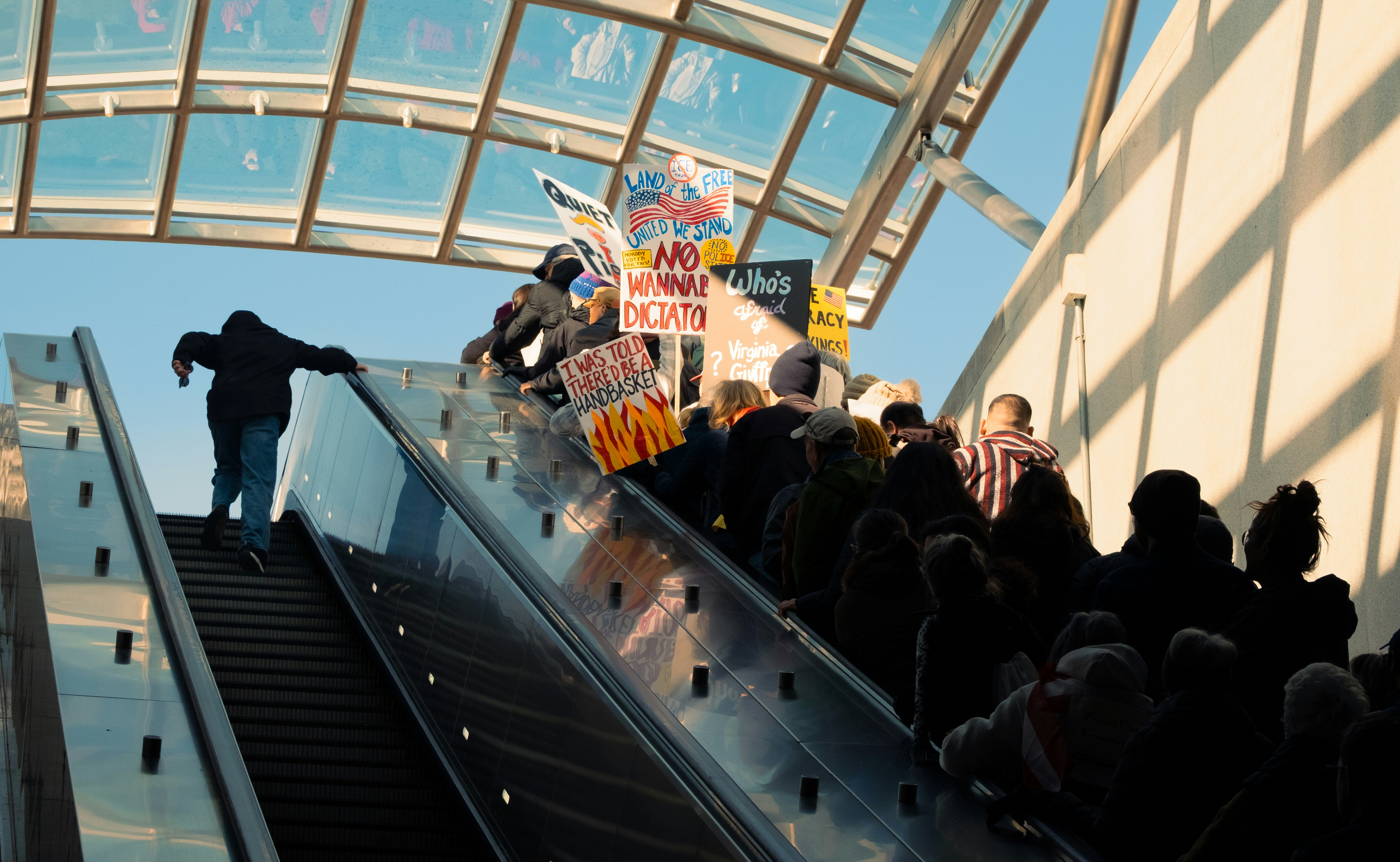 Gente en una escalera mecánica con carteles