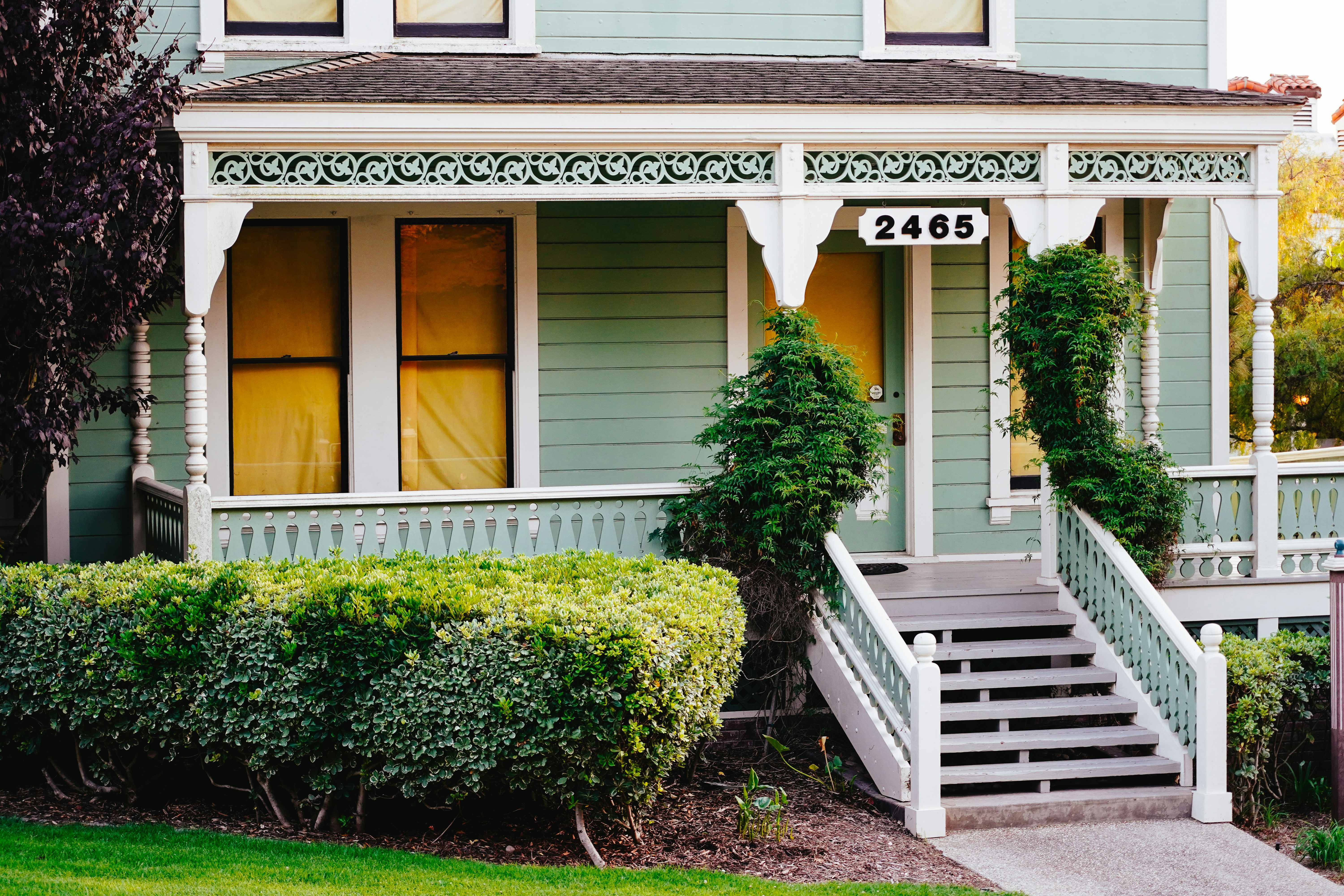 A light green house with a white porch.