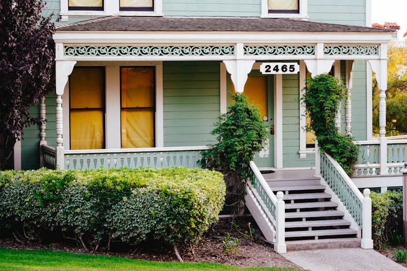 A porch with front steps and a white railing