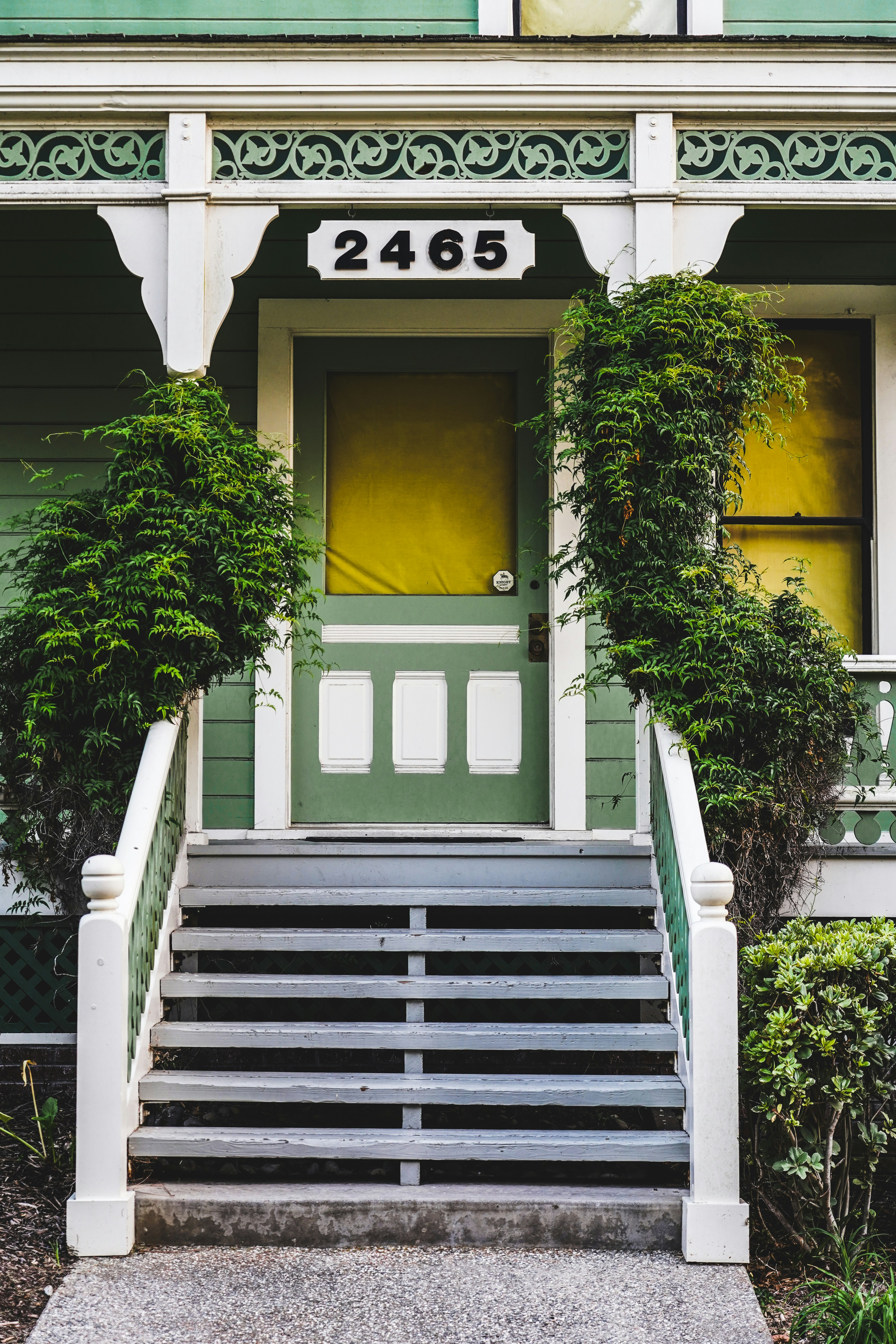 Green house with ornate porch and stairs