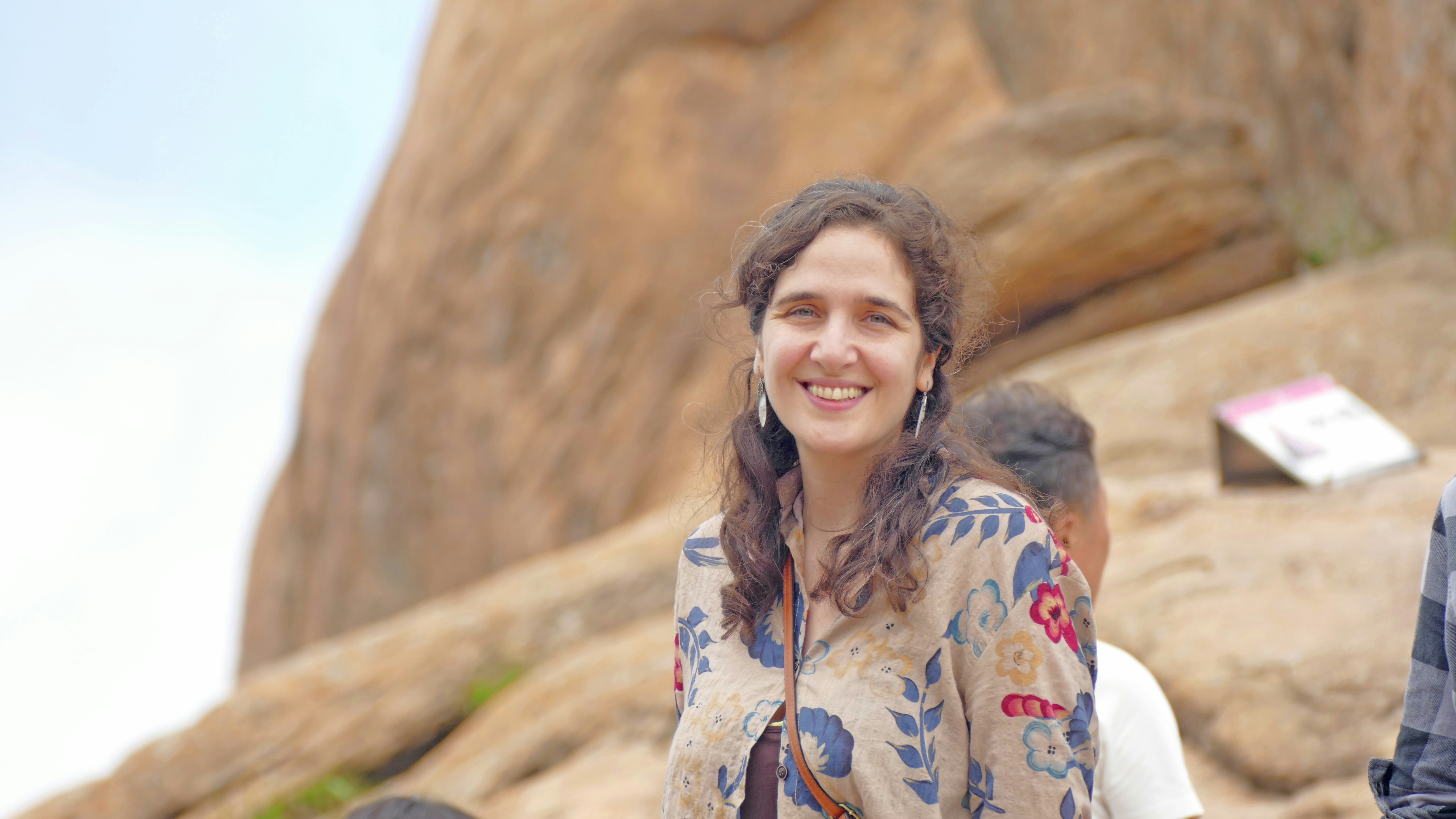 A smiling woman with curly hair outdoors