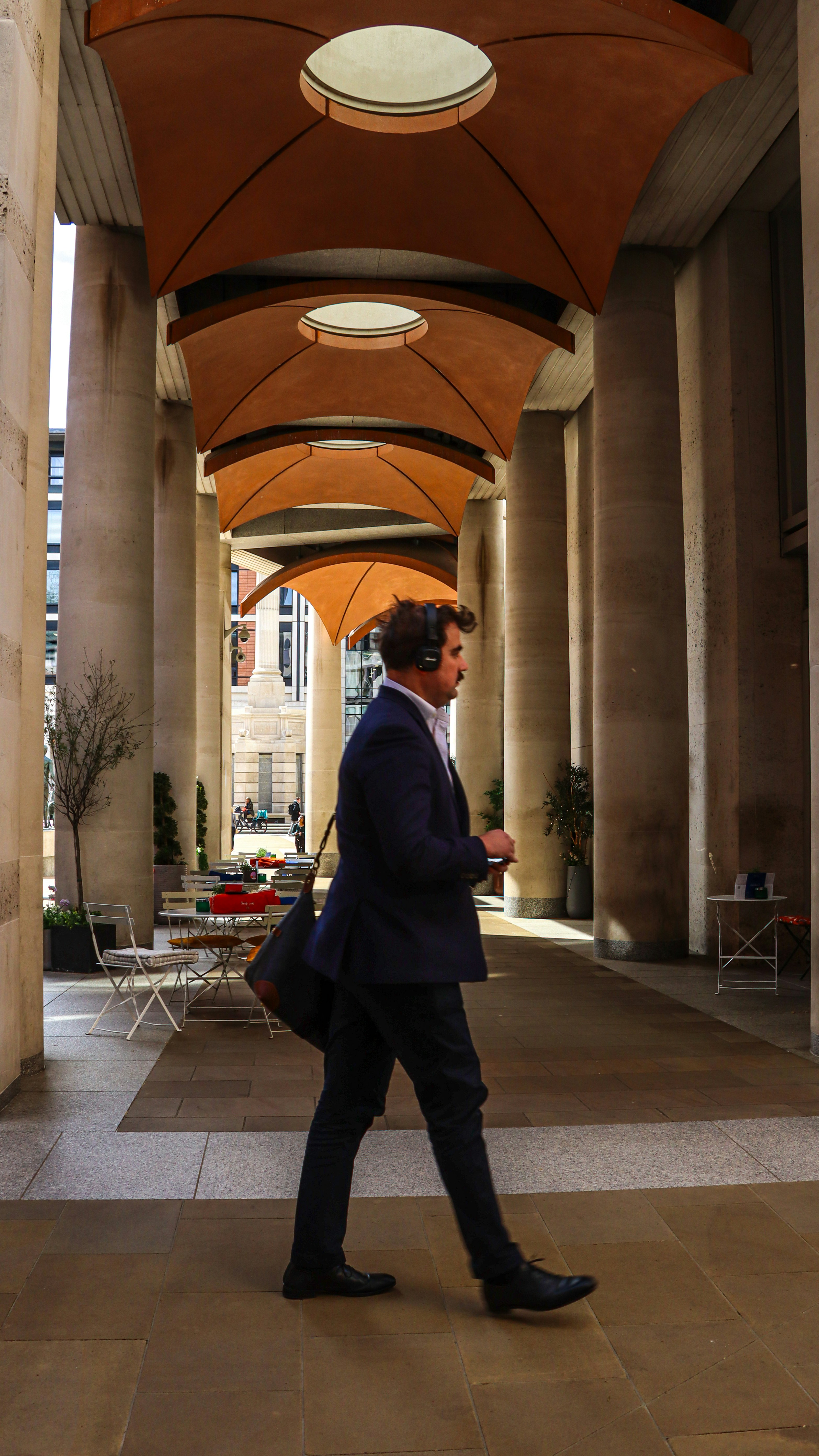 Man in suit walking with headphones and bag