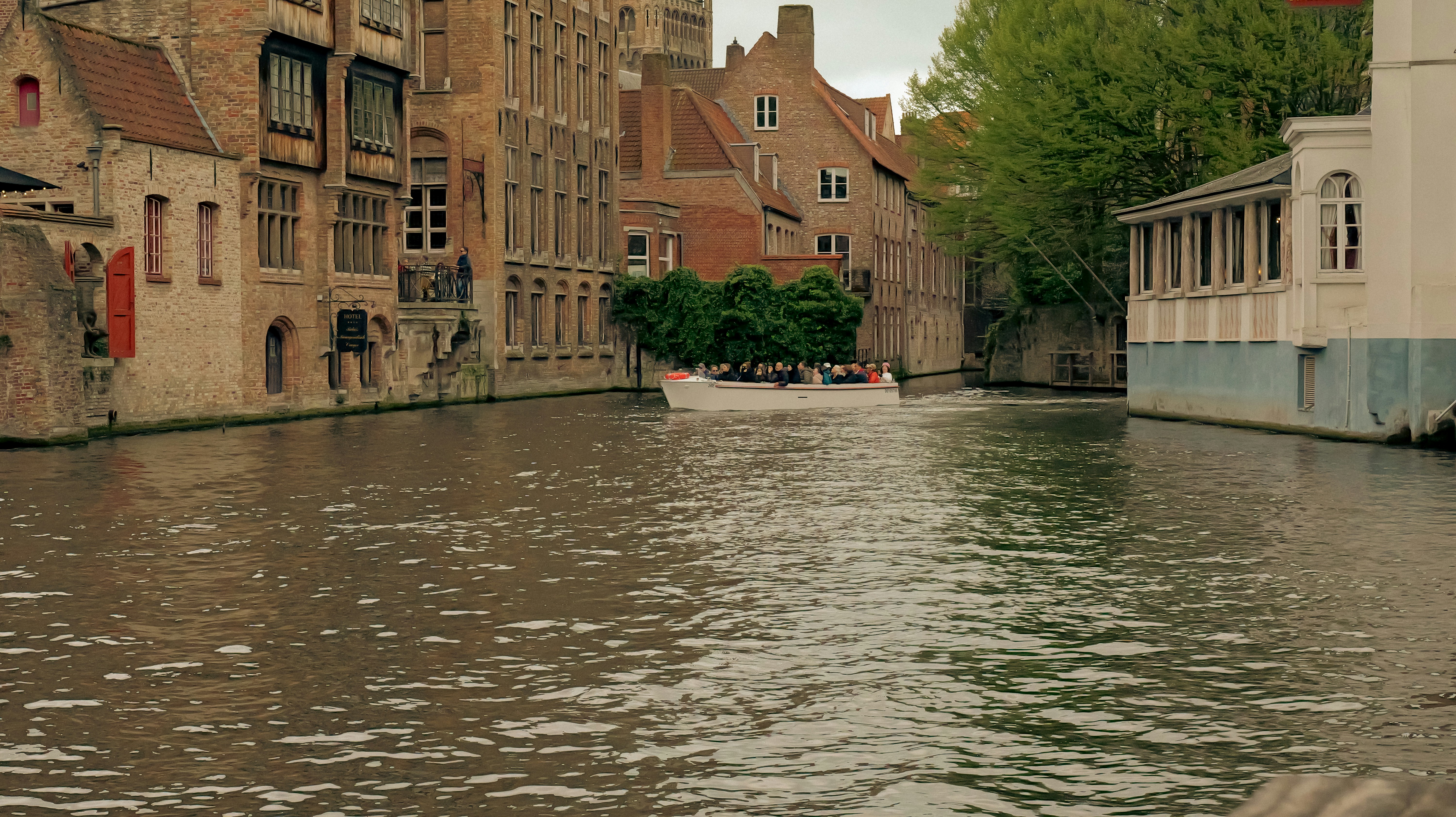 A boat travels down a canal lined with old buildings. - a-boat-travels-down-a-canal-lined-with-old-buildings-6Qc1jypexII
