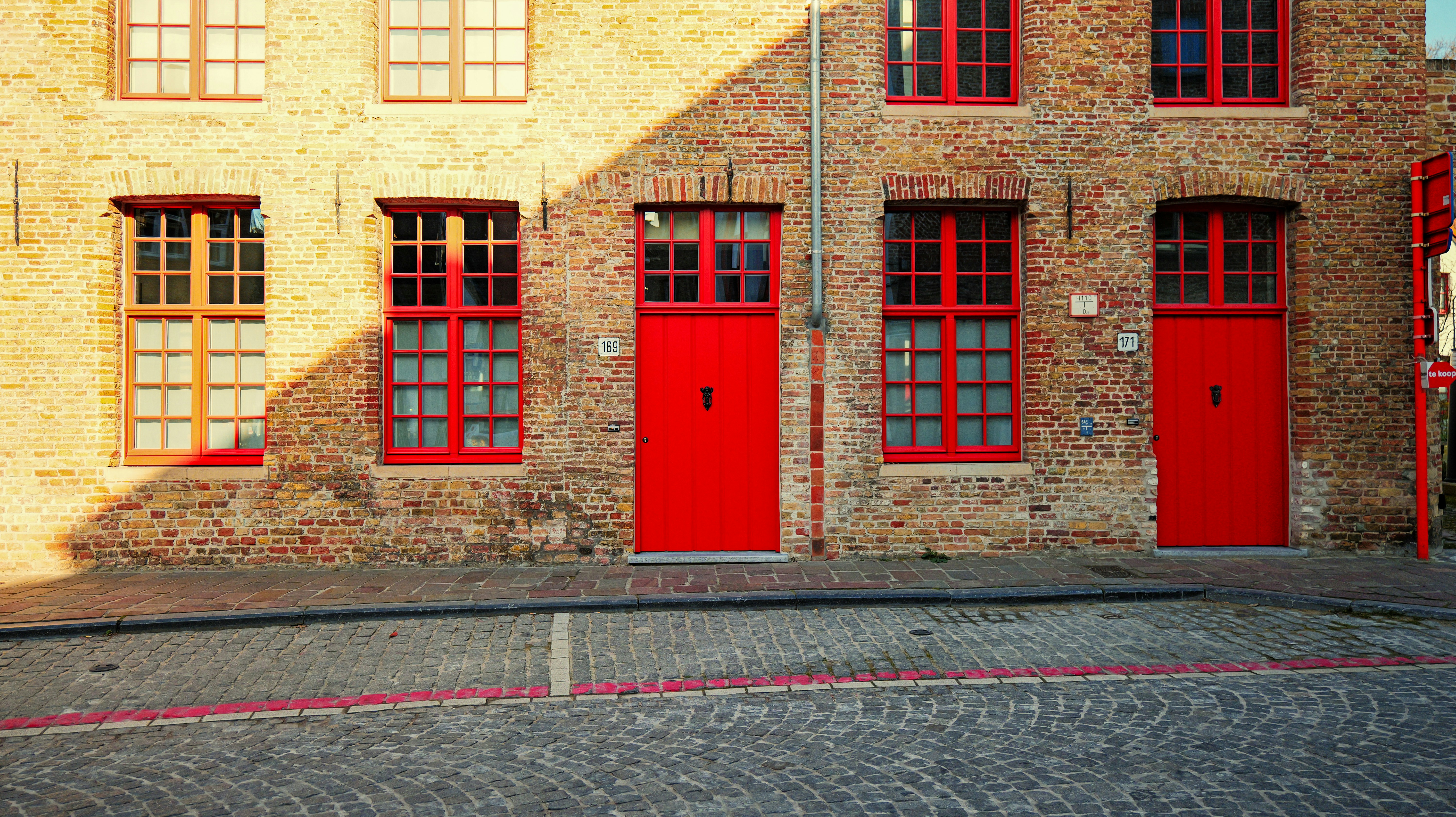 Brick building with red doors and windows - brick-building-with-red-doors-and-windows-rcS0r21JDQo