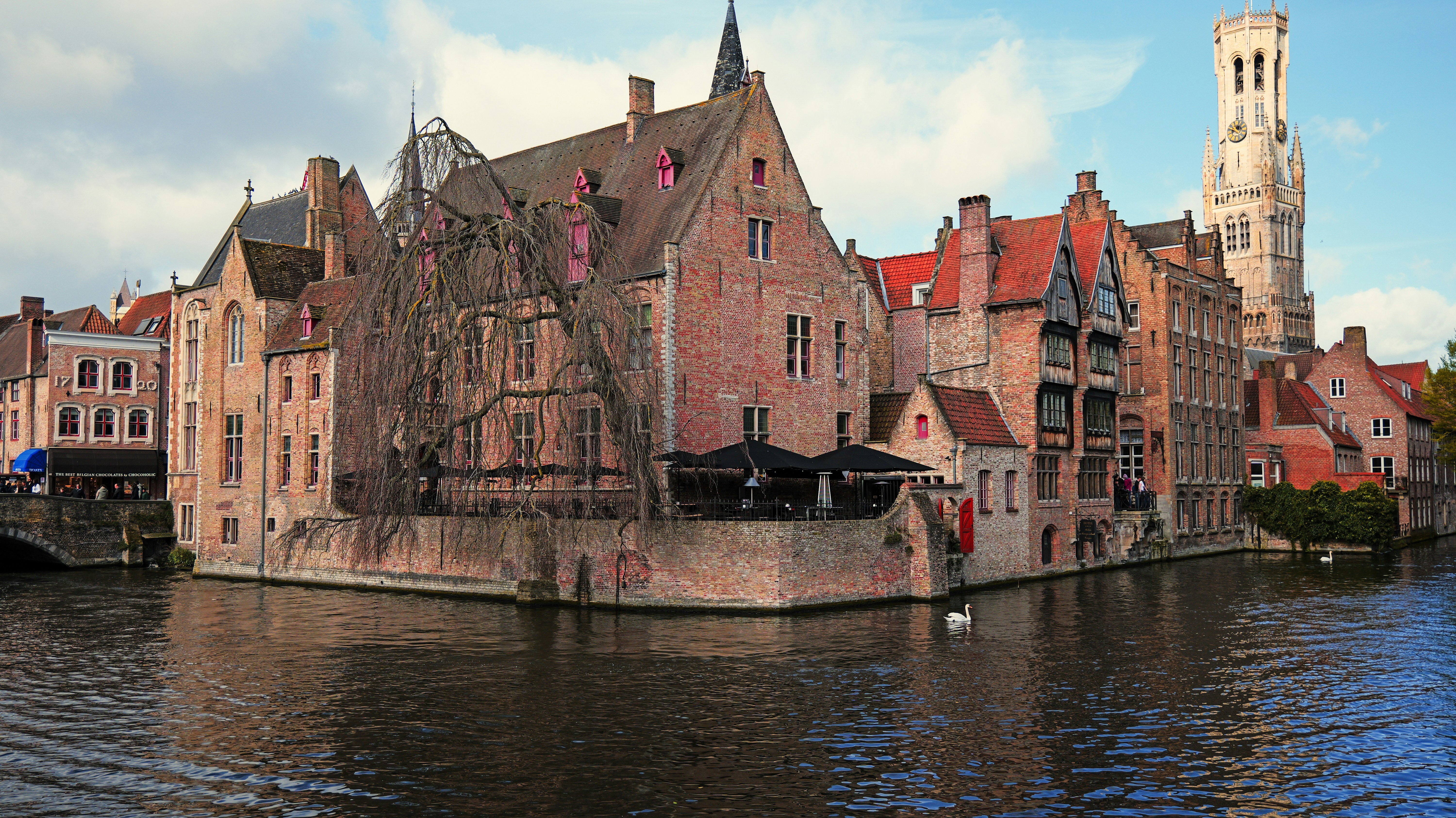 Historic buildings line a canal under a clear sky. - historic-buildings-line-a-canal-under-a-clear-sky-rPJQs6PunBk